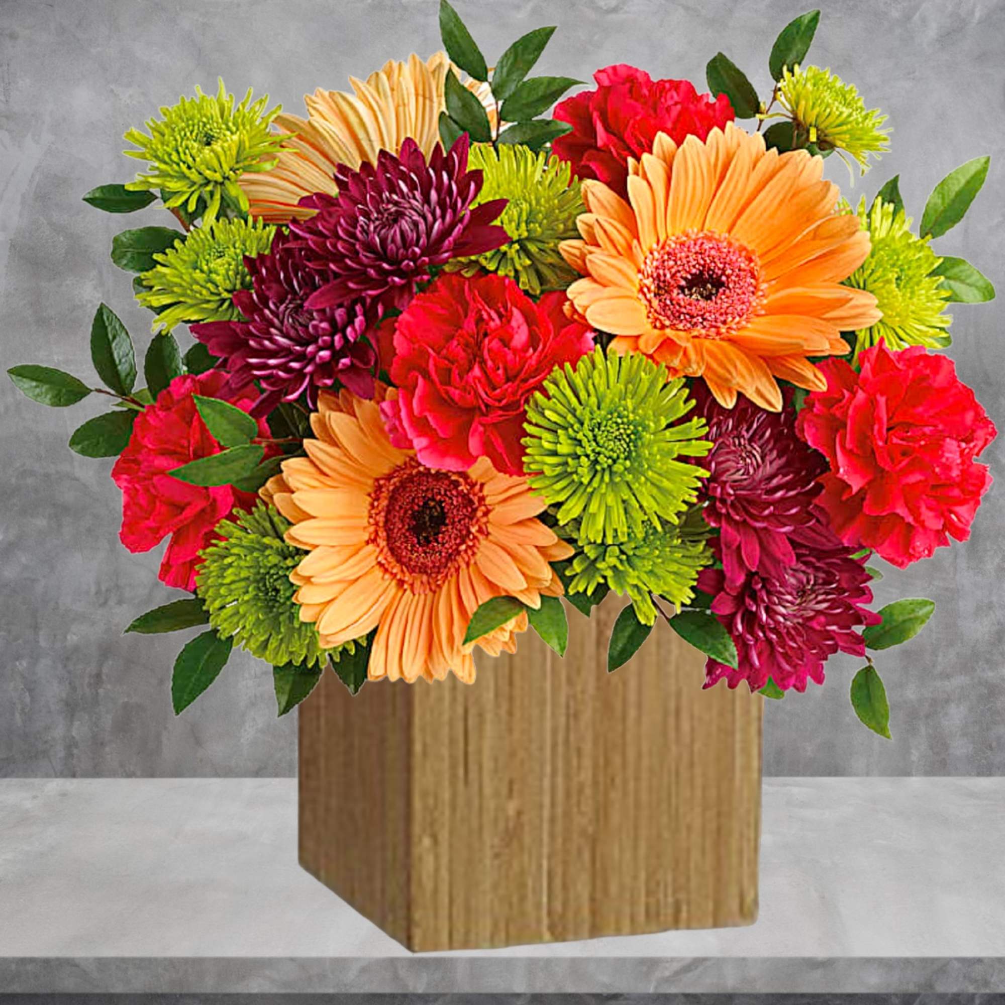 Bright mixed flower arrangement in a wooden cube vase