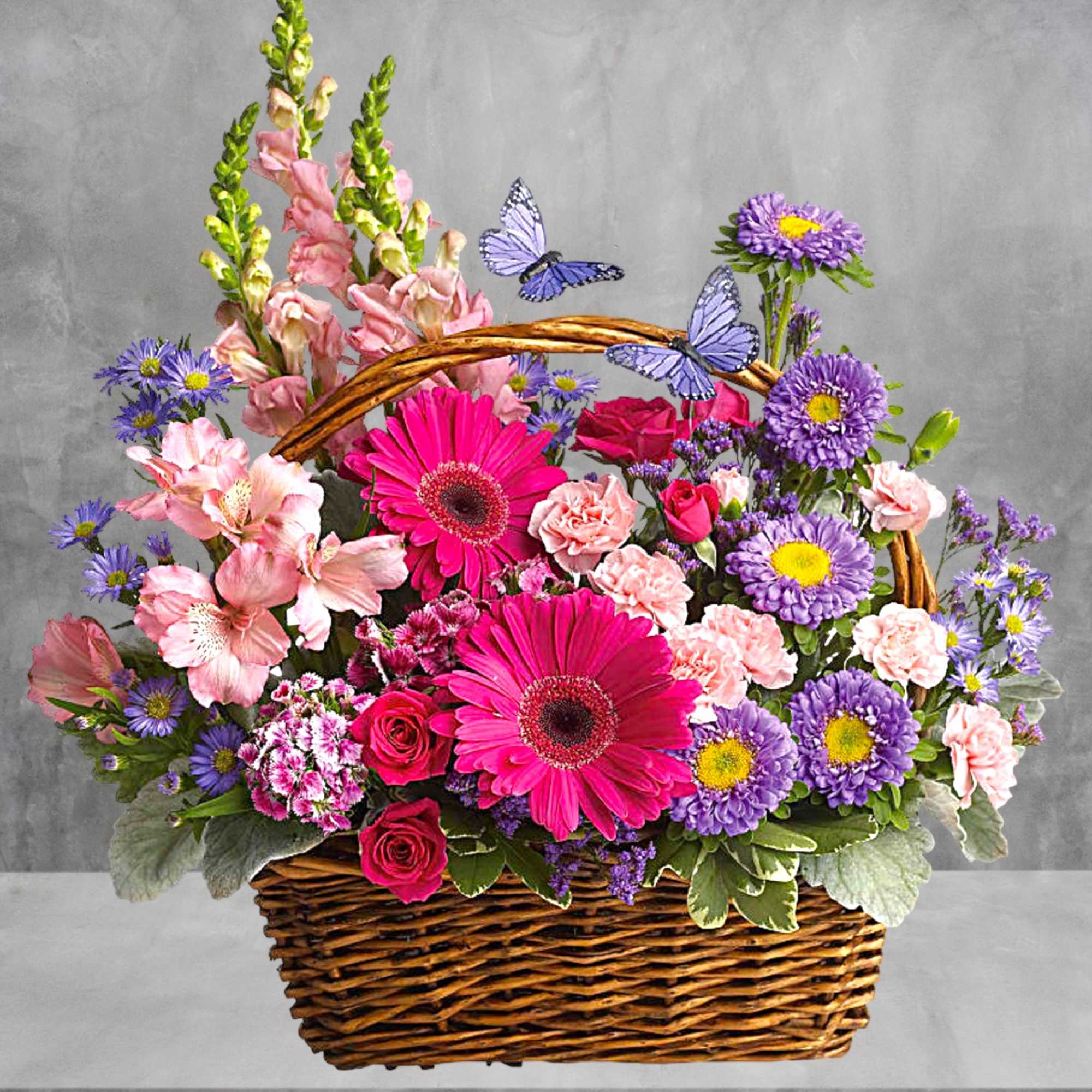 Basket arrangement with pink gerberas, roses, and purple daisies