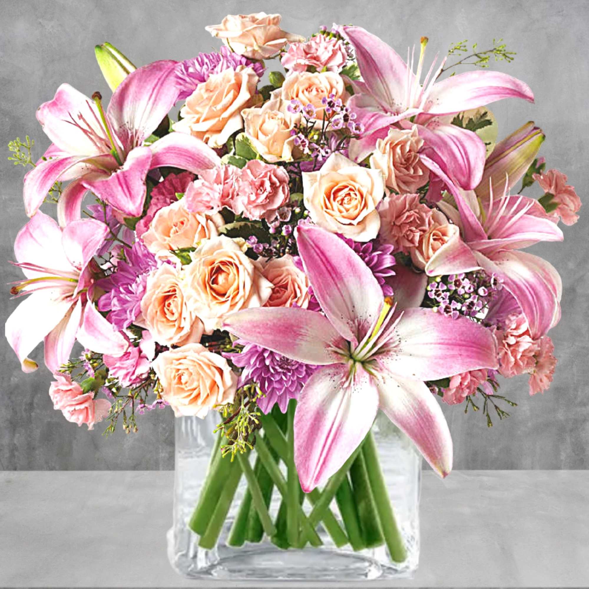 Pink lilies and peach roses arranged in a clear glass vase, photo 2 of 5
