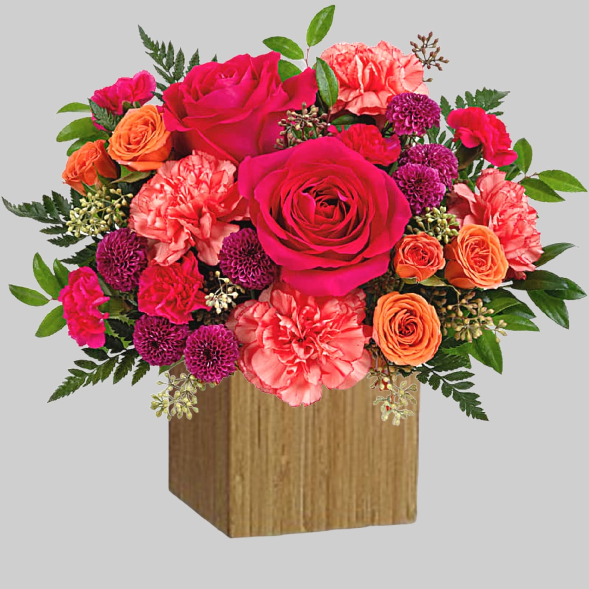 Bright pink and orange flower arrangement in a wooden cube vase