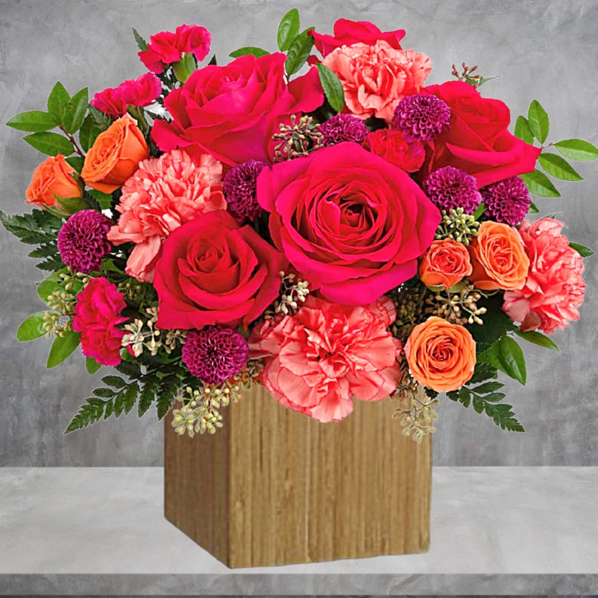 Bright pink and orange flower arrangement in a wooden box