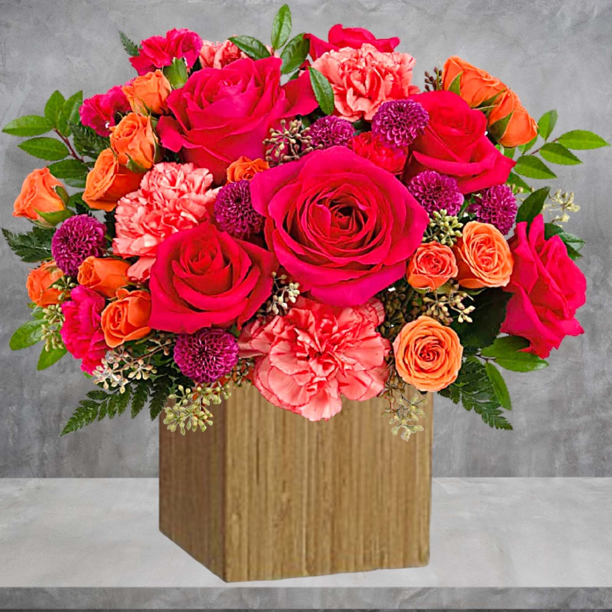 Bright pink and orange rose bouquet in a wooden cube vase