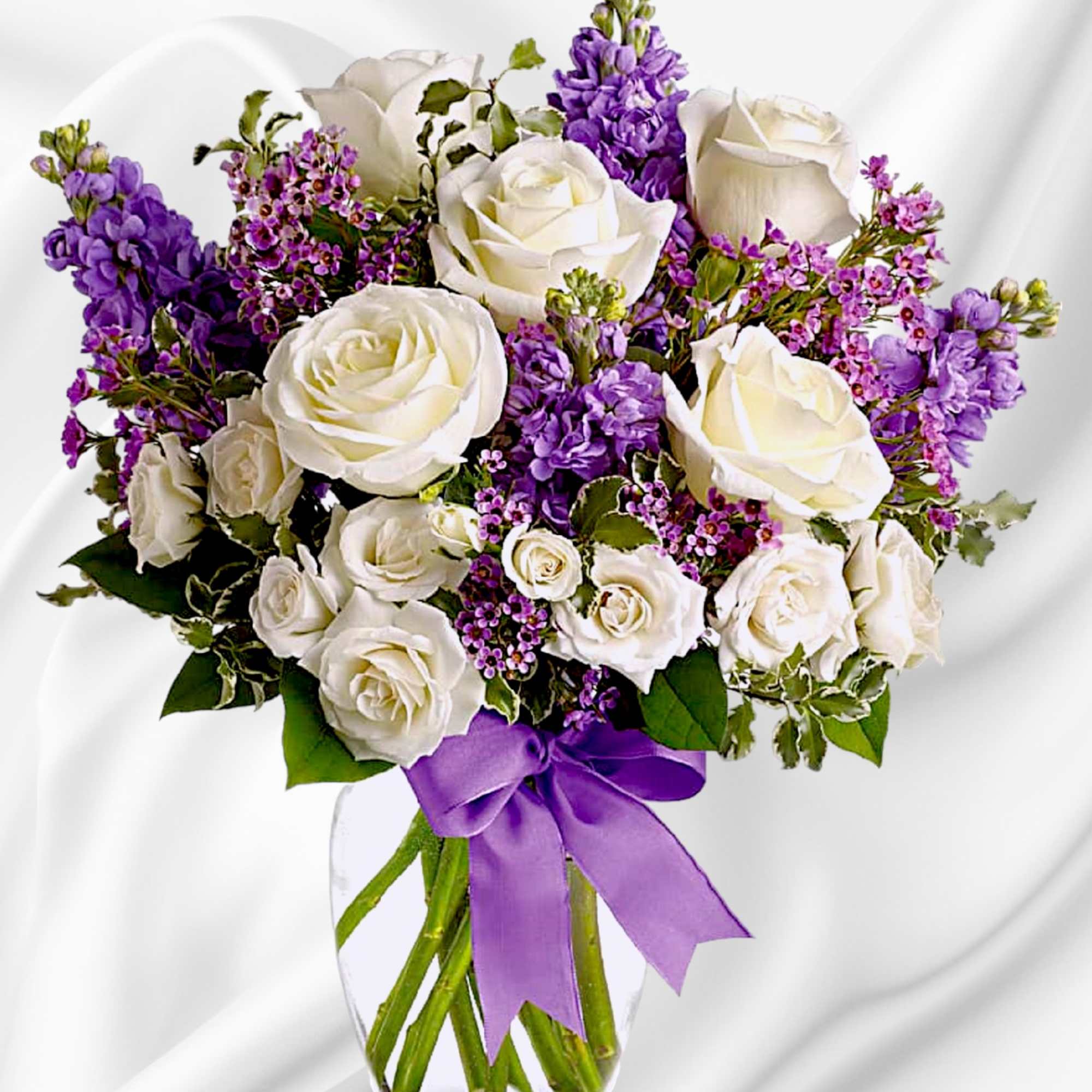 White roses and purple flowers in a clear glass vase with a purple ribbon, photo 4 of 5