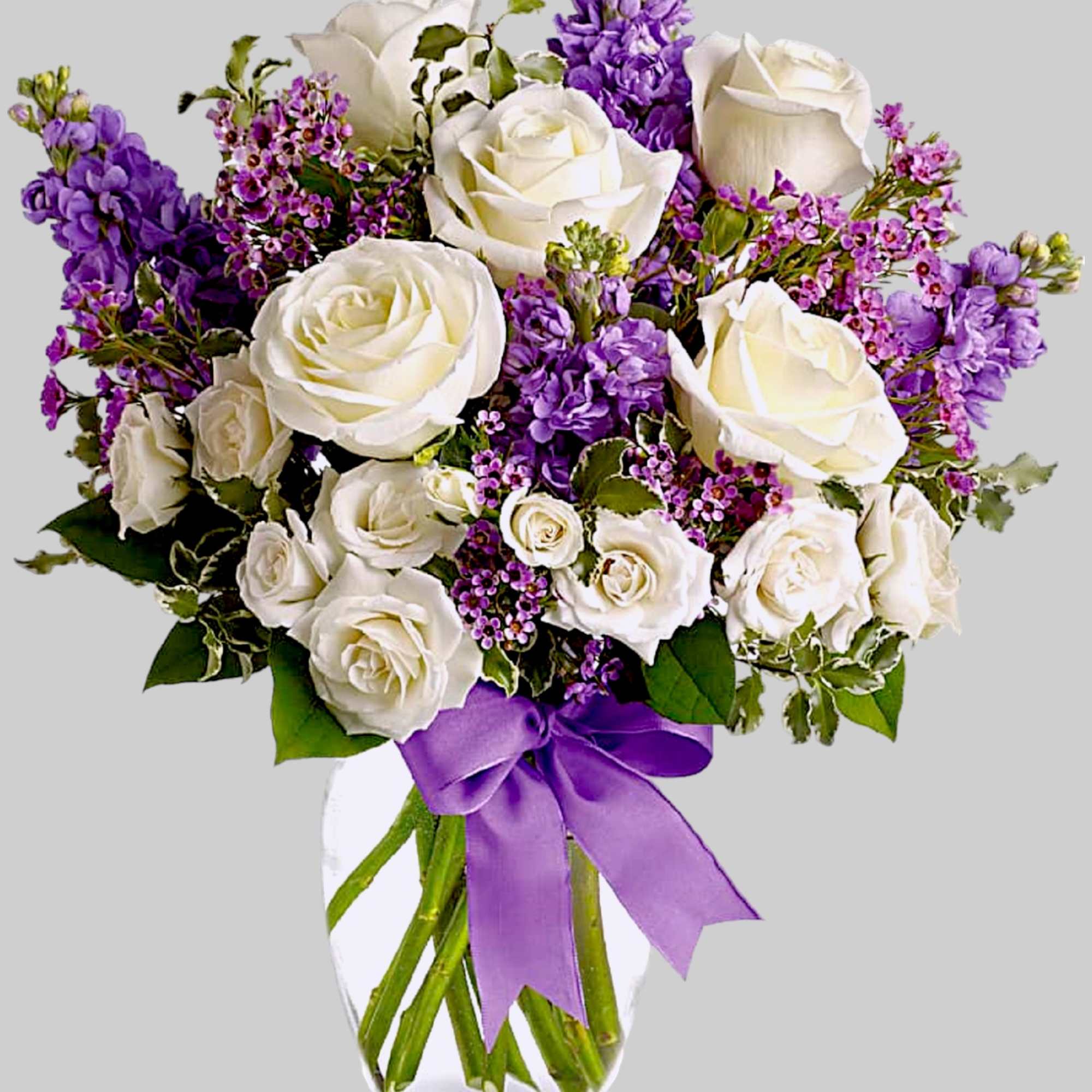 White roses and purple flowers in a clear glass vase with a purple ribbon, photo 5 of 5