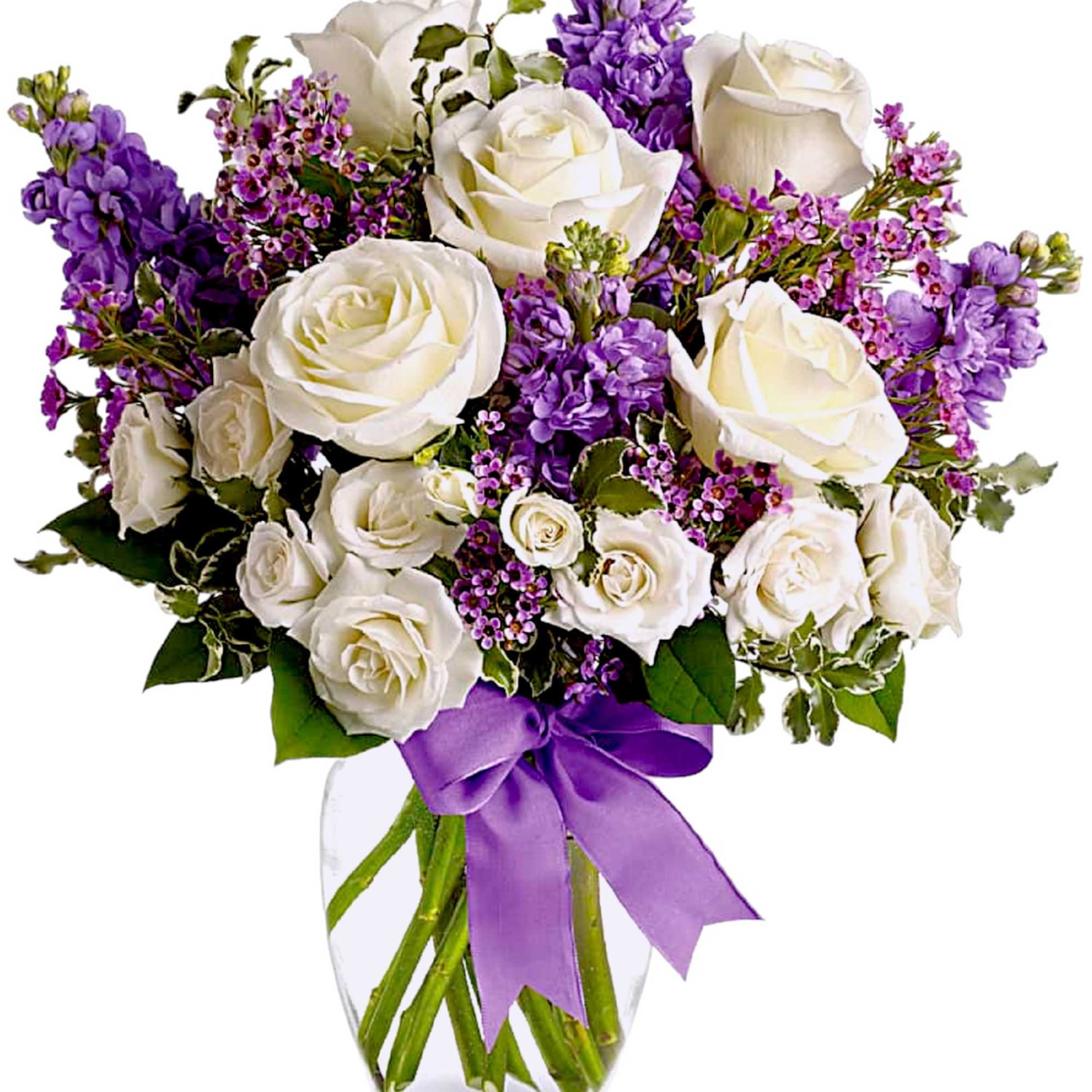 White roses and purple flowers arranged in a clear glass vase with a purple ribbon