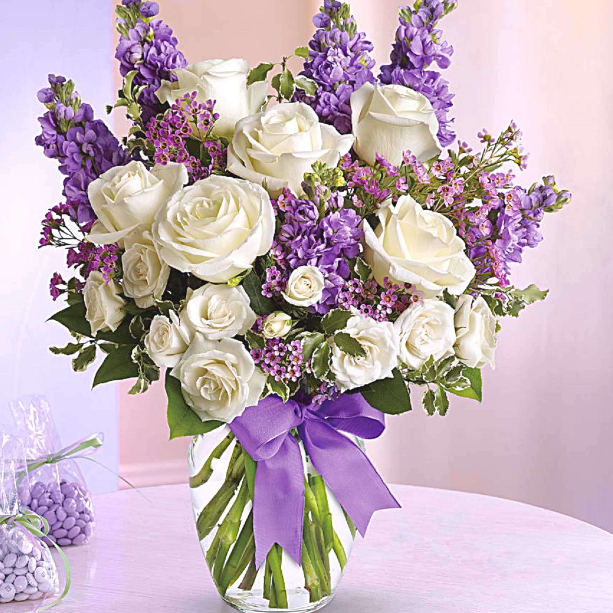 White roses and purple flowers in a glass vase with a purple ribbon, photo 3 of 5