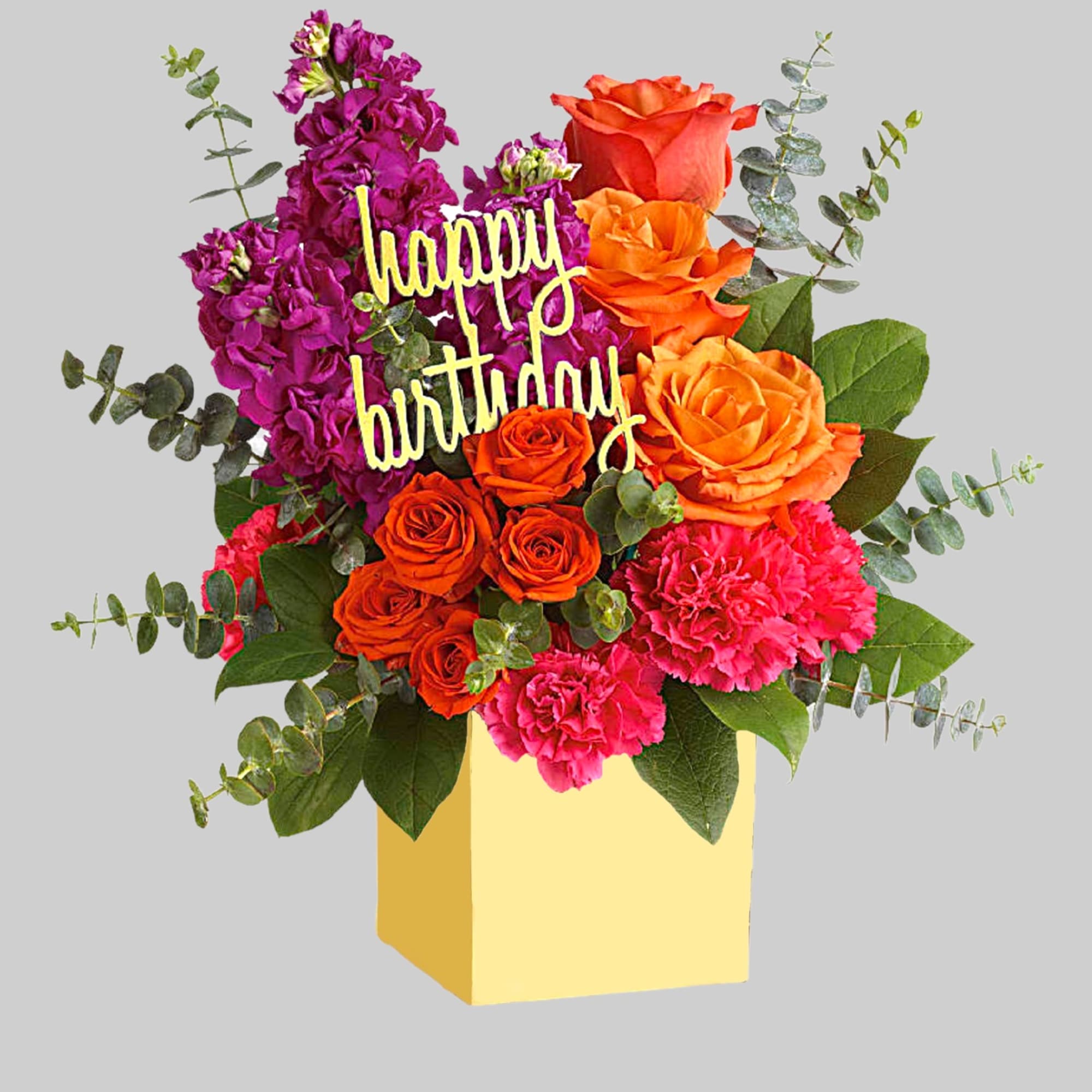 Birthday bouquet with orange roses, pink carnations, and purple flowers in a yellow box