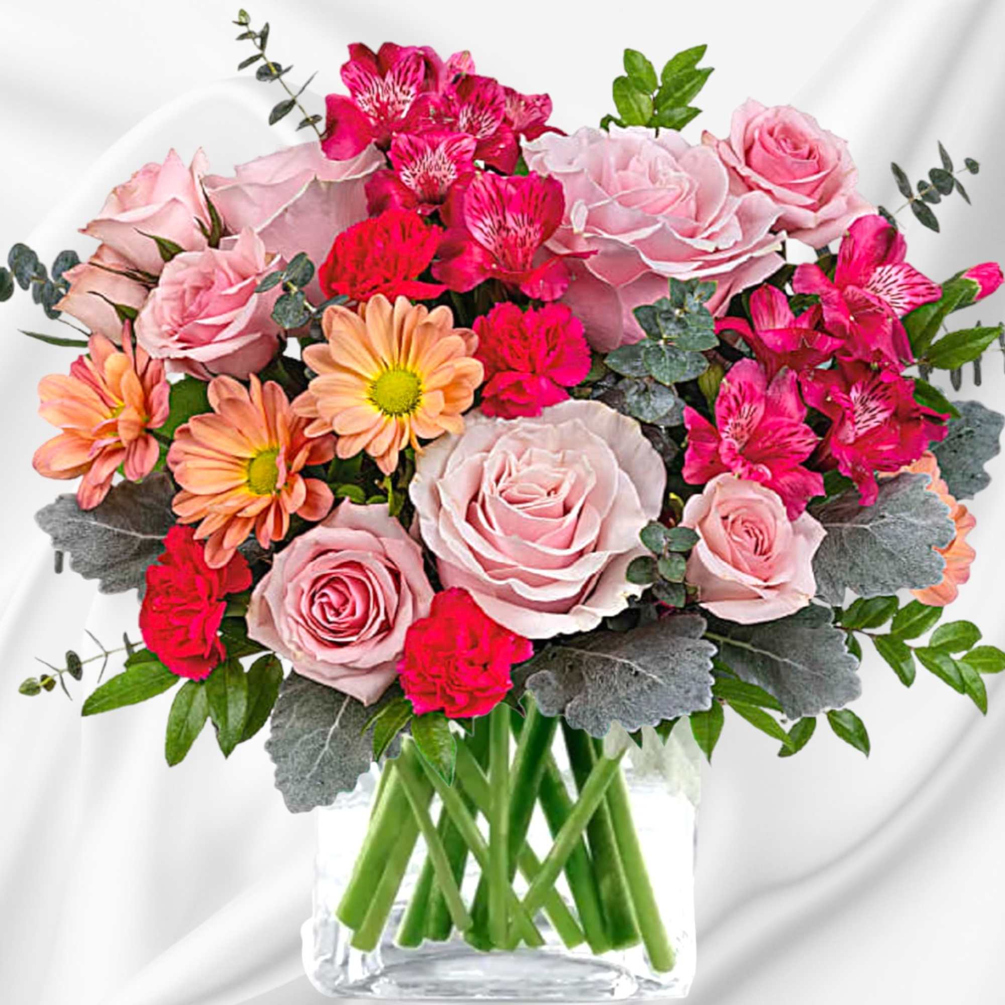 Pink roses and bright mixed flowers arranged in a clear glass vase