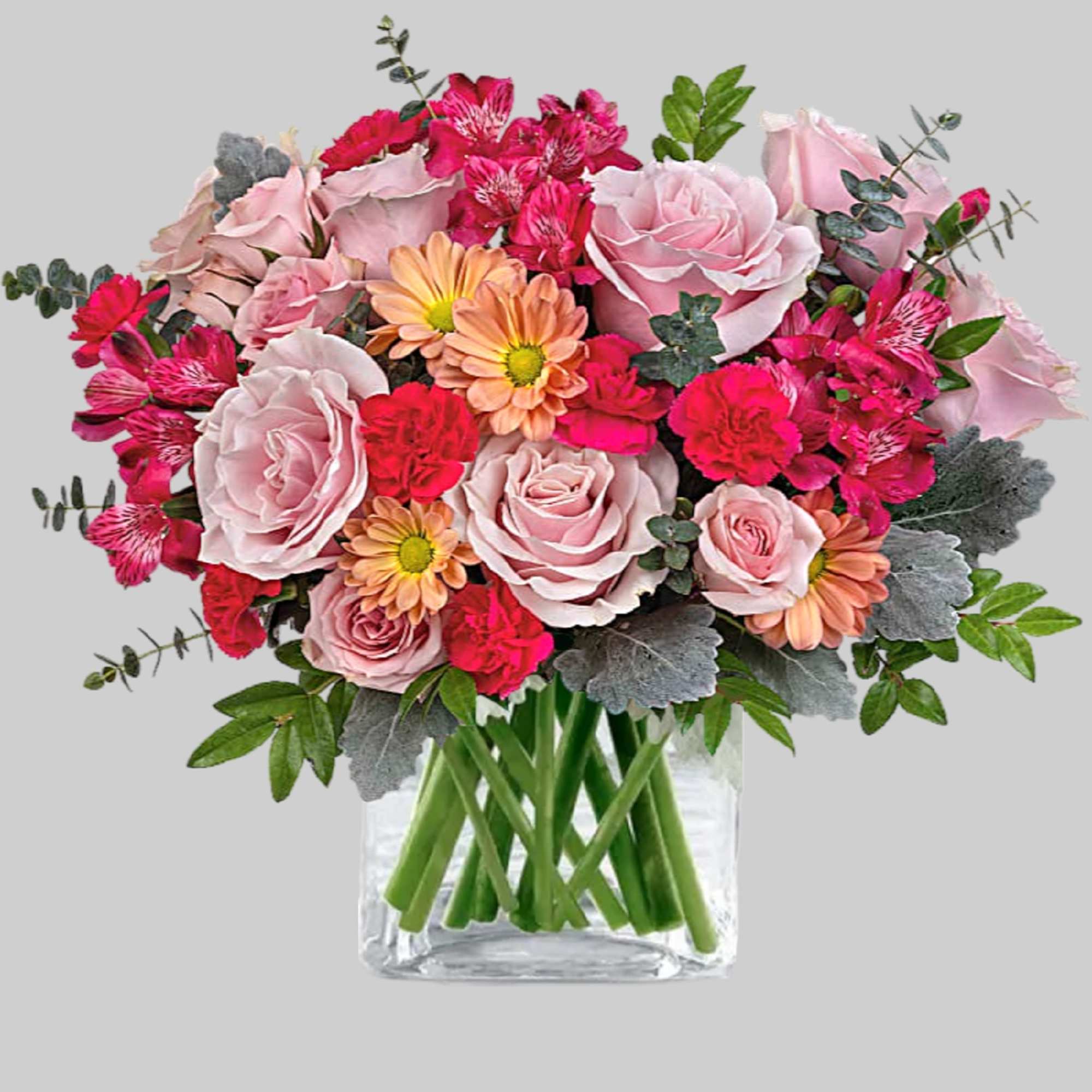 Pink roses and mixed blooms in a clear glass vase