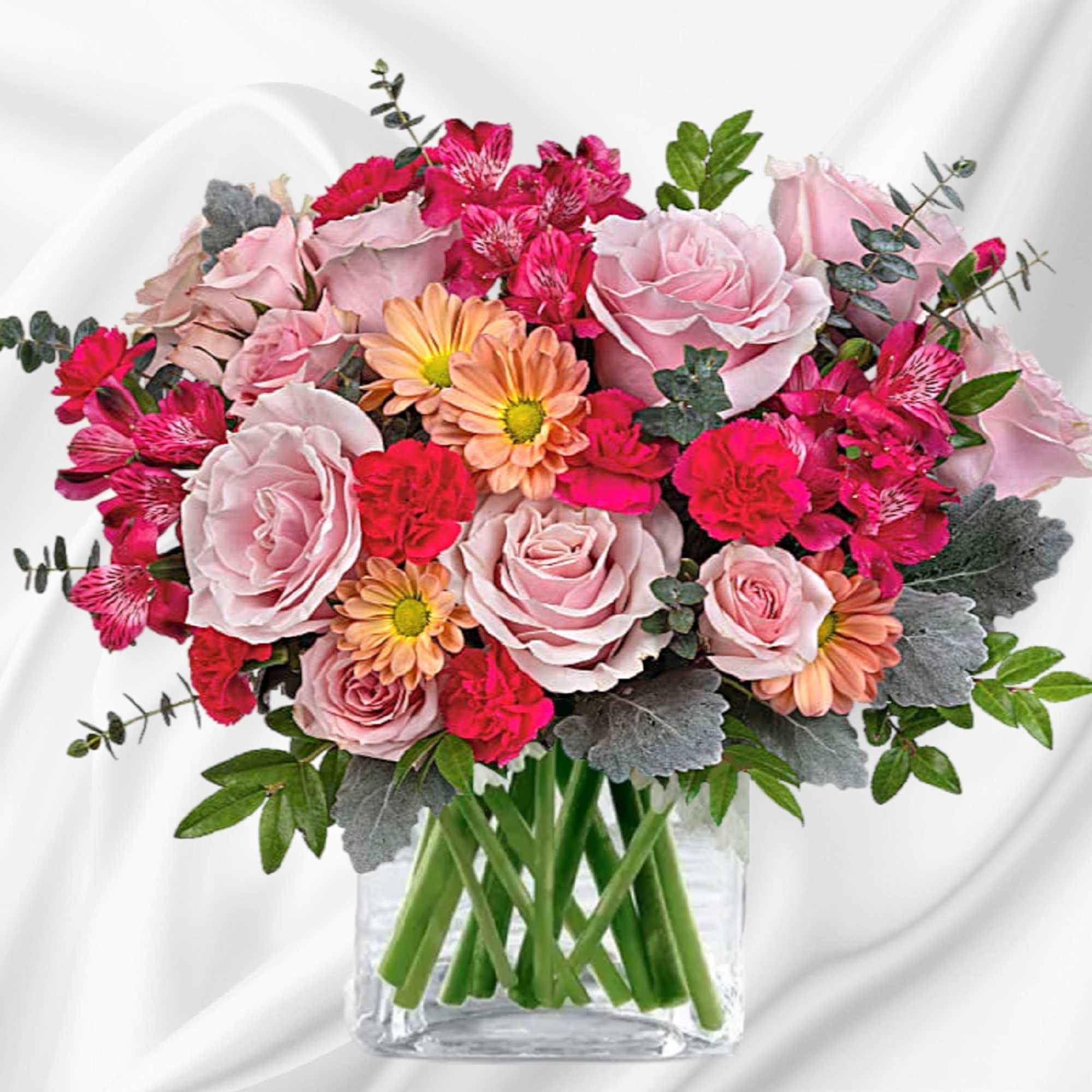 Pink roses and mixed blooms in a clear square vase
