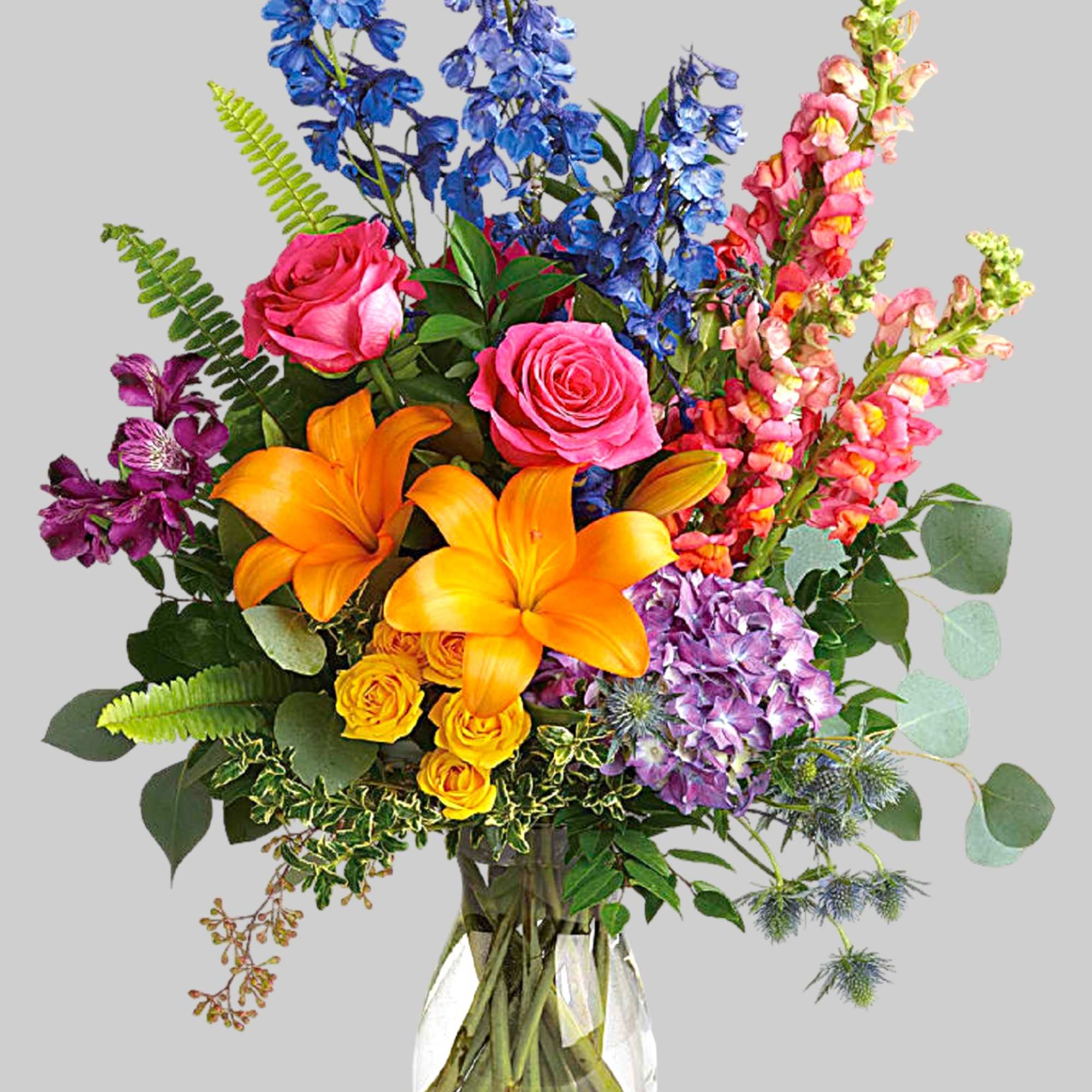 Colorful bouquet with roses, lilies, delphinium, and snapdragons in a glass vase