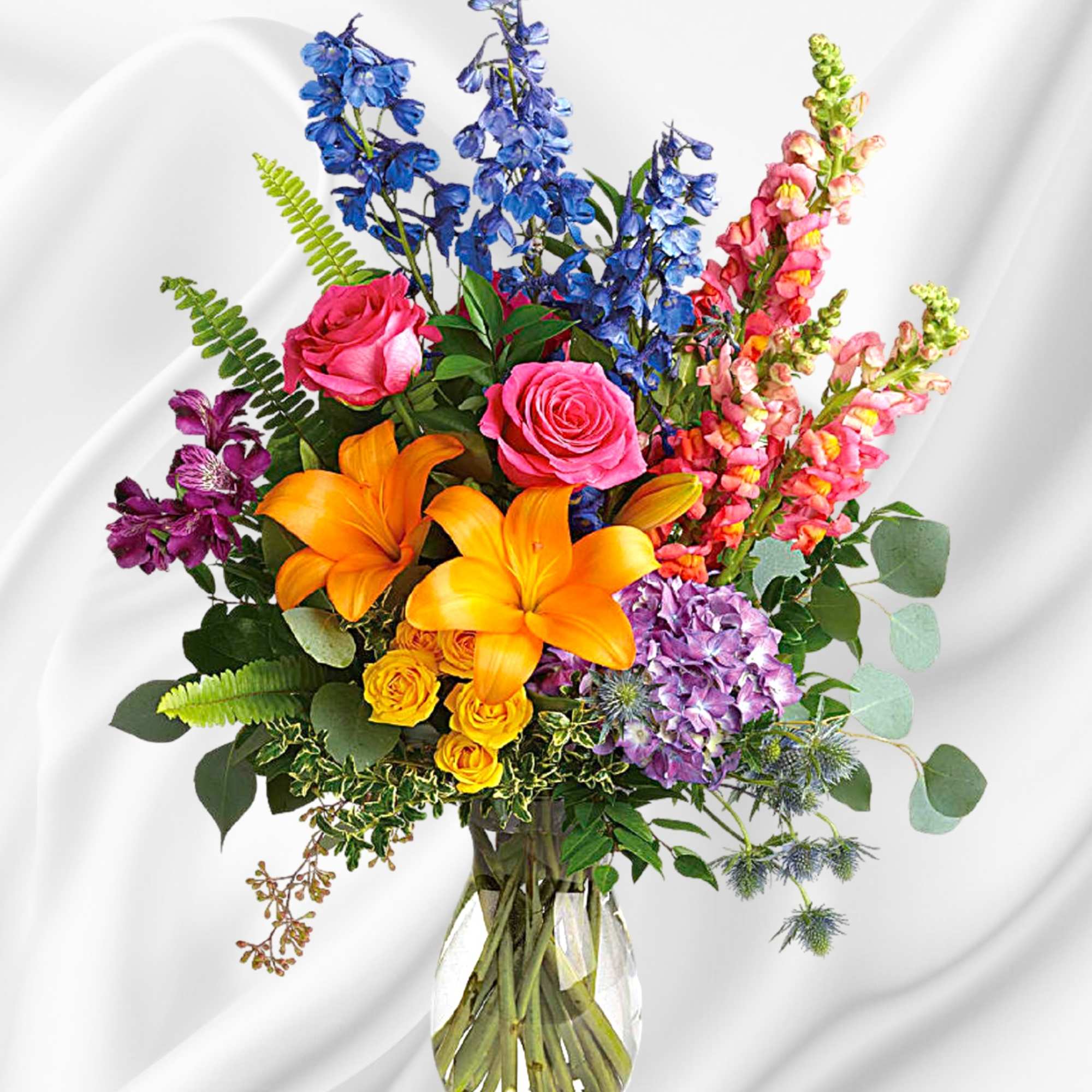 Colorful bouquet with roses, lilies, and snapdragons in a clear glass vase
