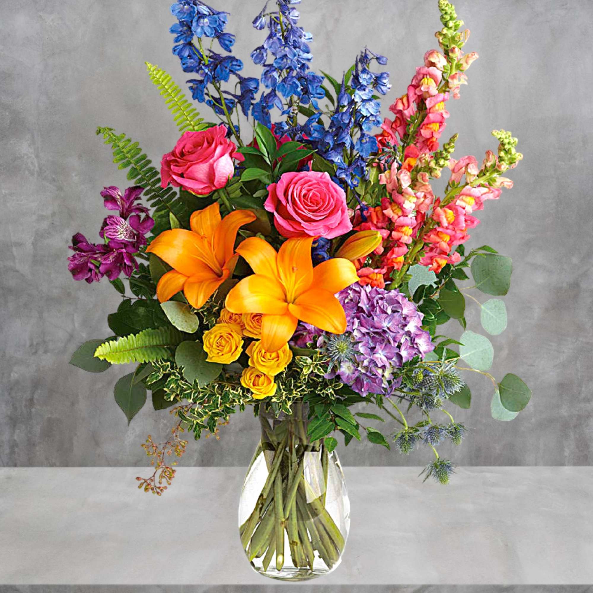 Colorful bouquet with roses, lilies, hydrangea, and snapdragons in a glass vase