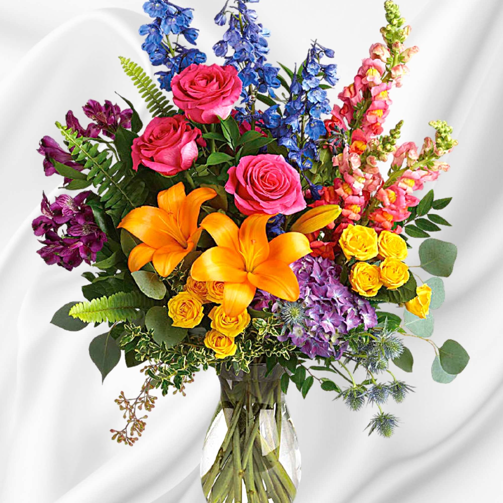 Colorful bouquet of roses, lilies, and snapdragons in a clear glass vase