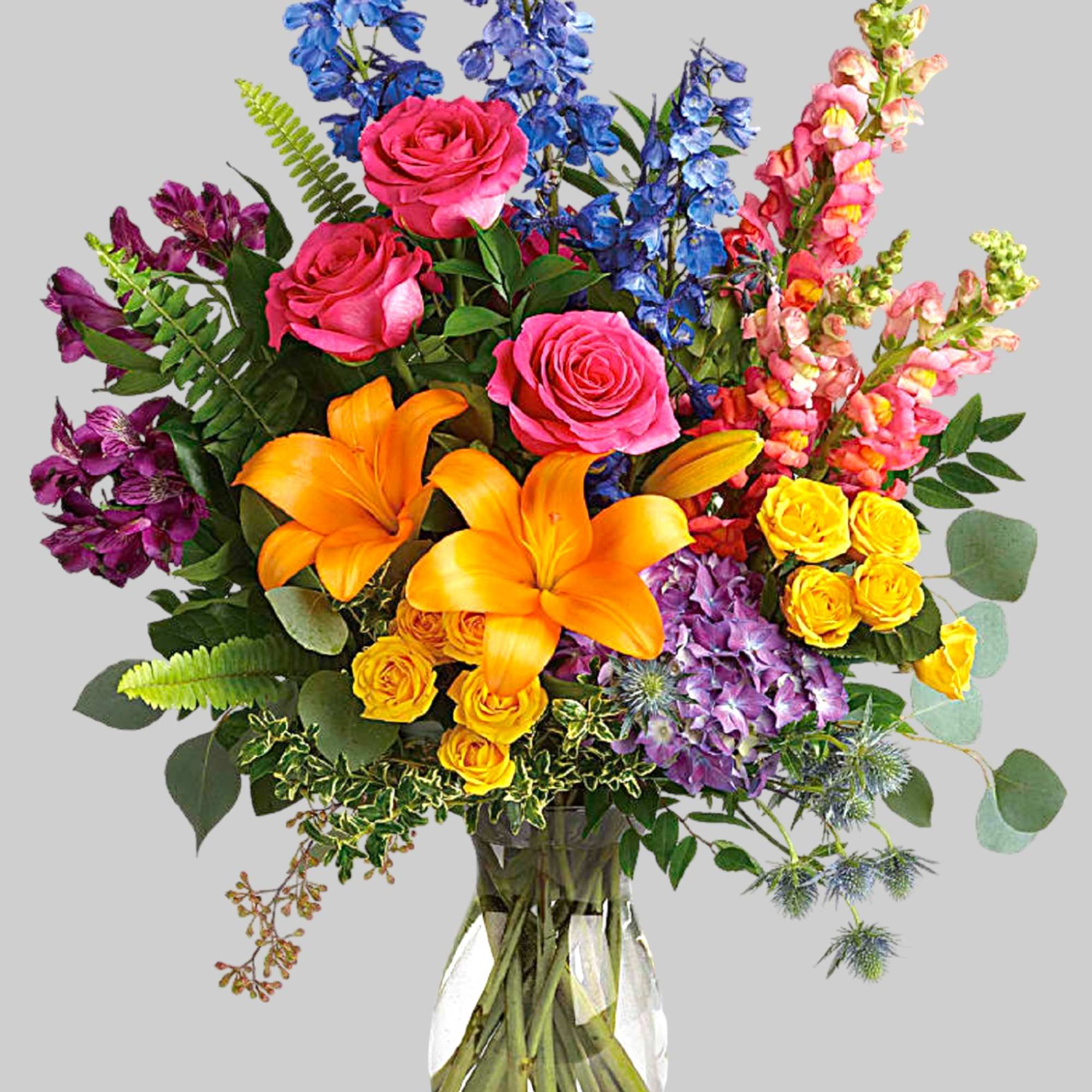 Colorful mixed bouquet in a clear glass vase with roses and lilies