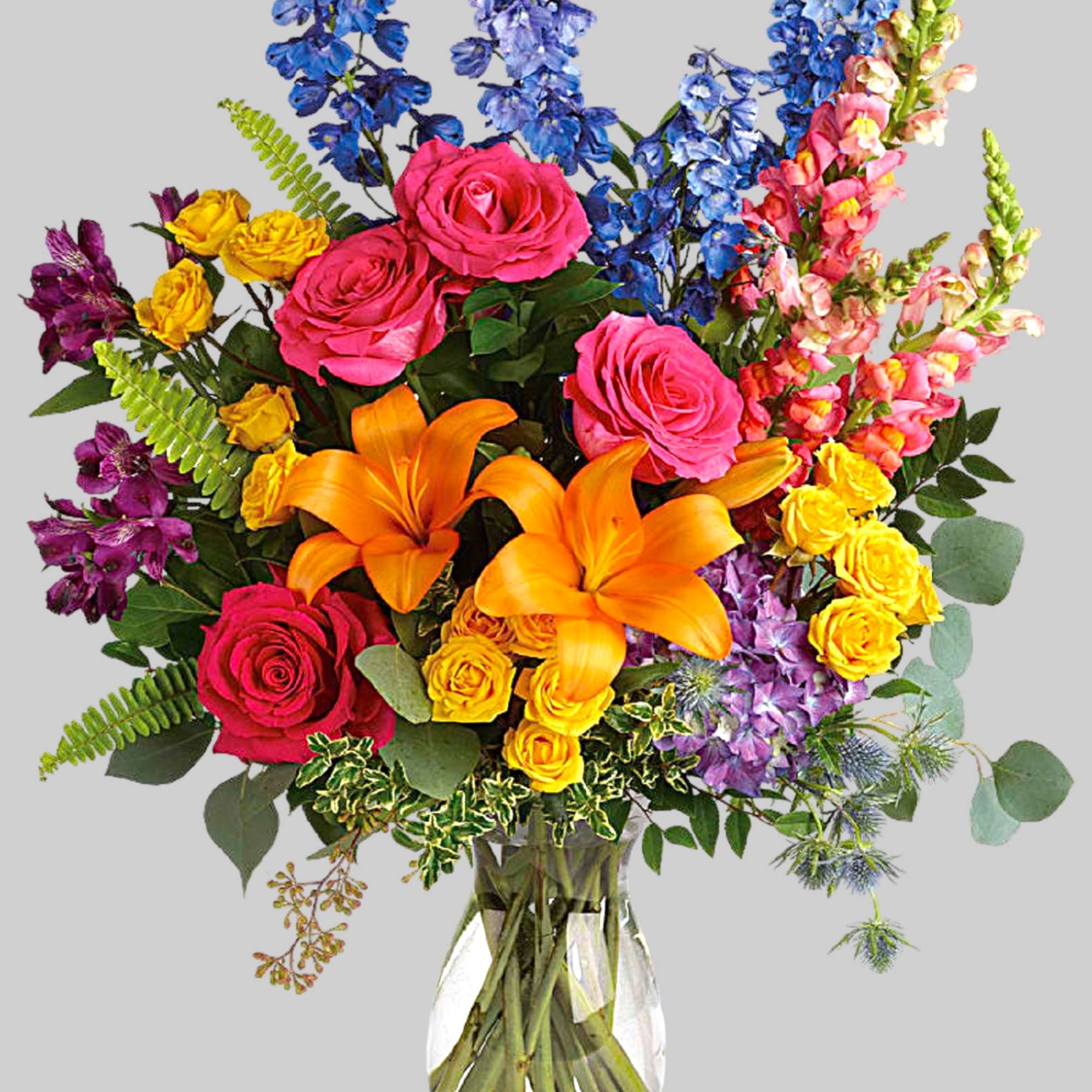 Colorful bouquet of roses, lilies, and mixed blooms in a clear glass vase