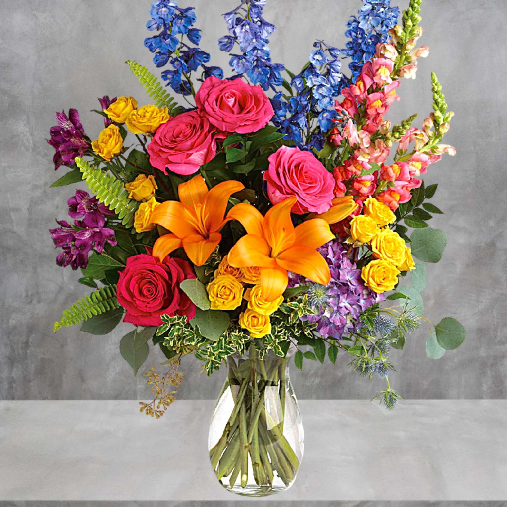 Colorful bouquet of roses, lilies, and snapdragons in a glass vase