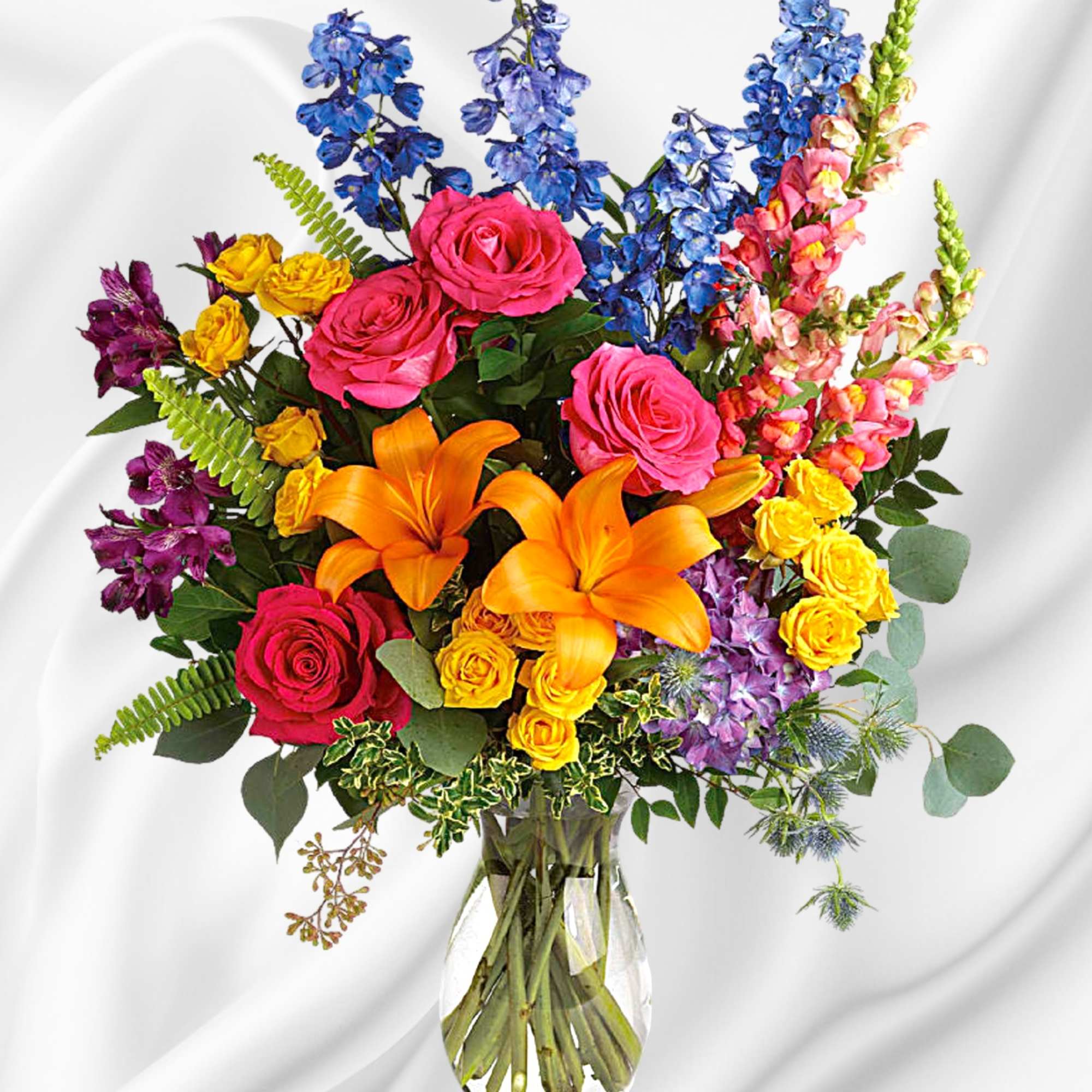 Colorful bouquet of roses, lilies, and snapdragons in a clear glass vase