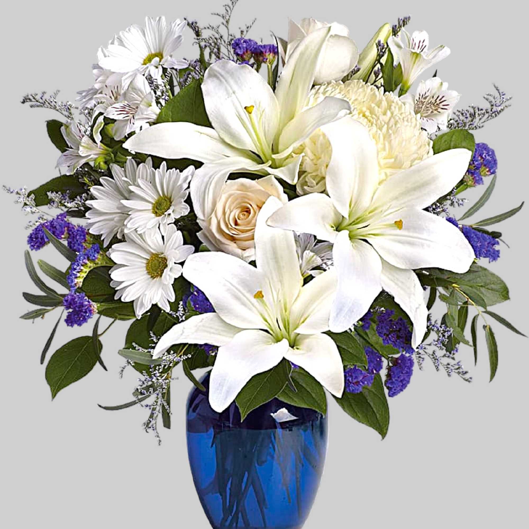 White lilies and daisies in a blue glass vase
