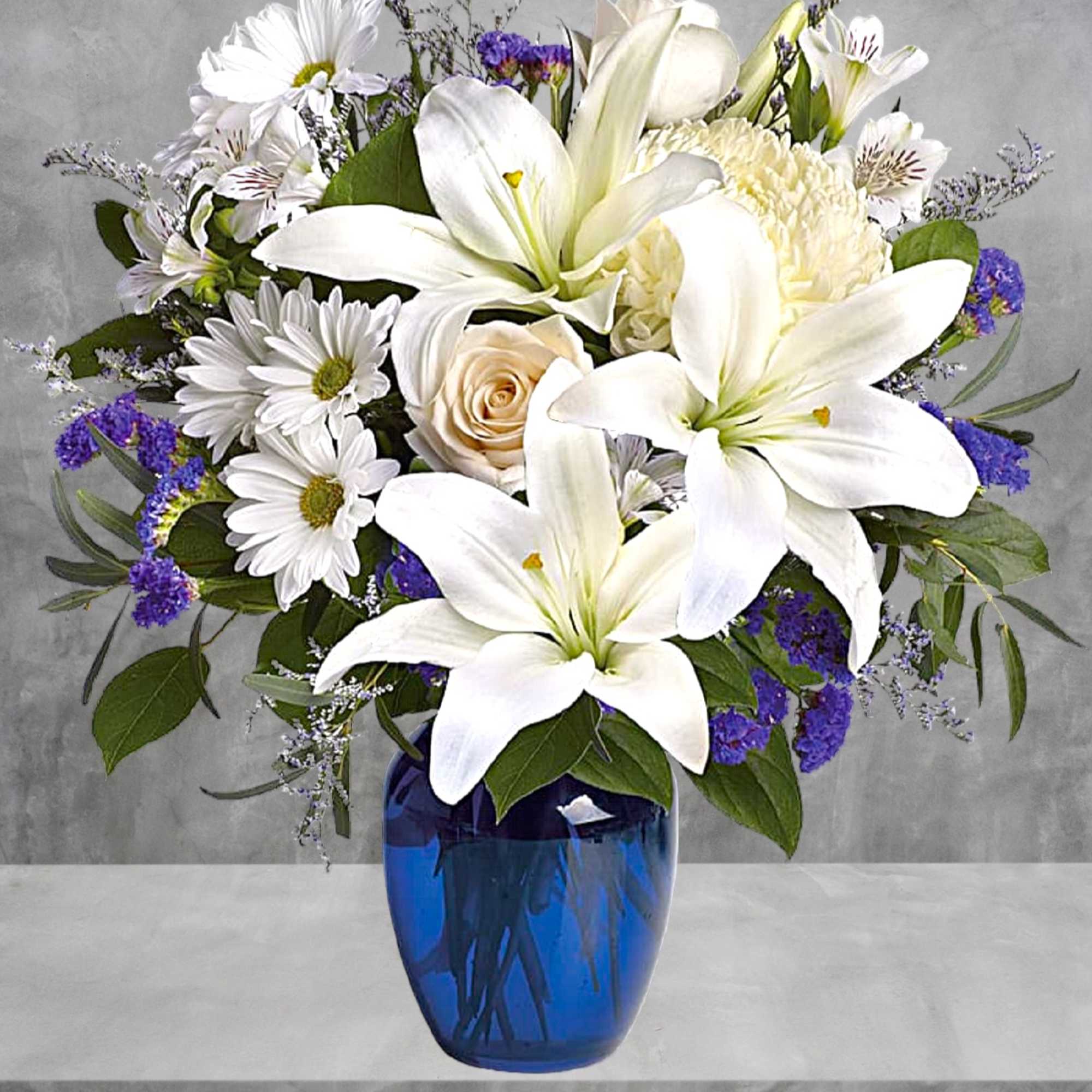 White lilies and daisies arranged in a blue glass vase, photo 3 of 4