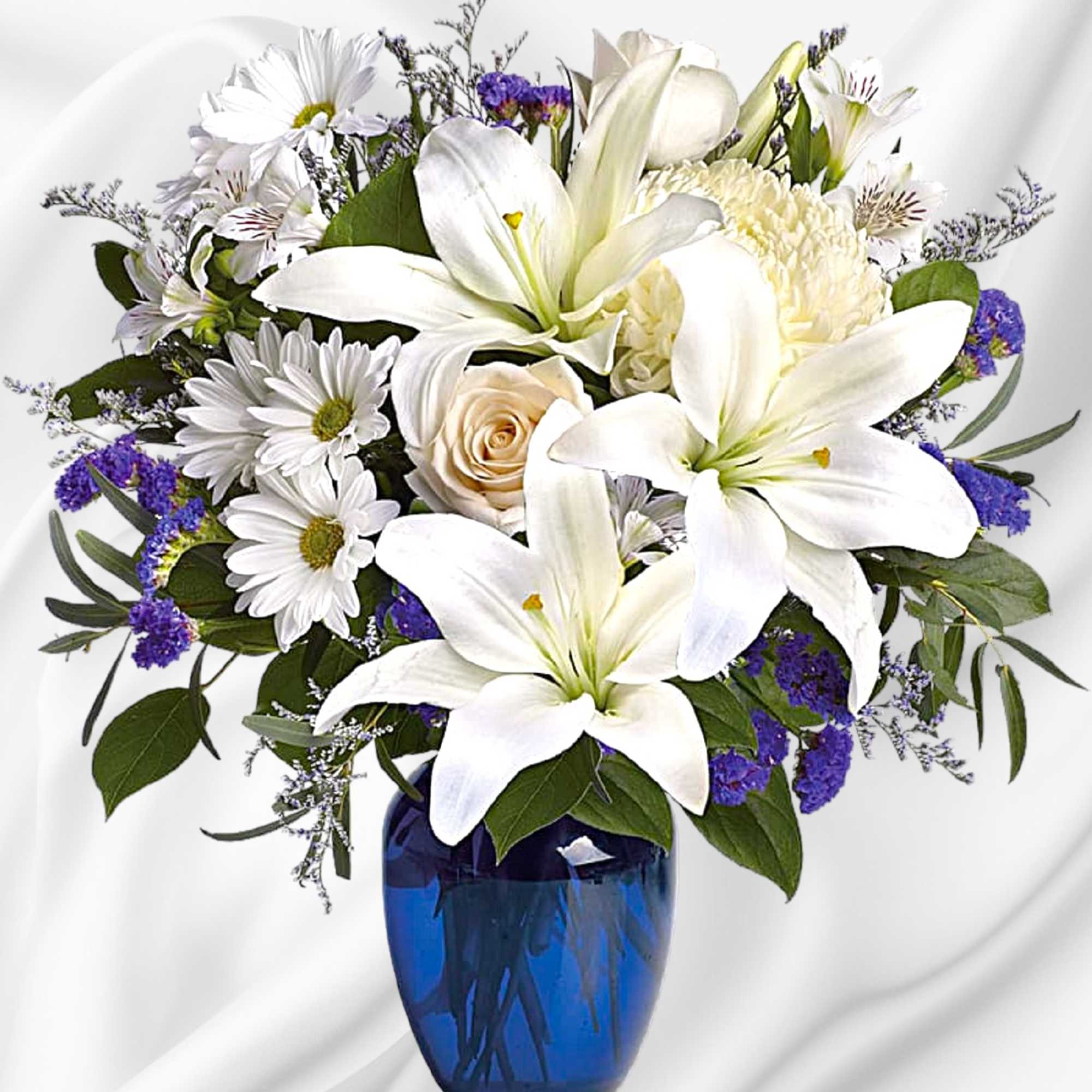 White lilies and daisies arranged in a blue glass vase, photo 2 of 4