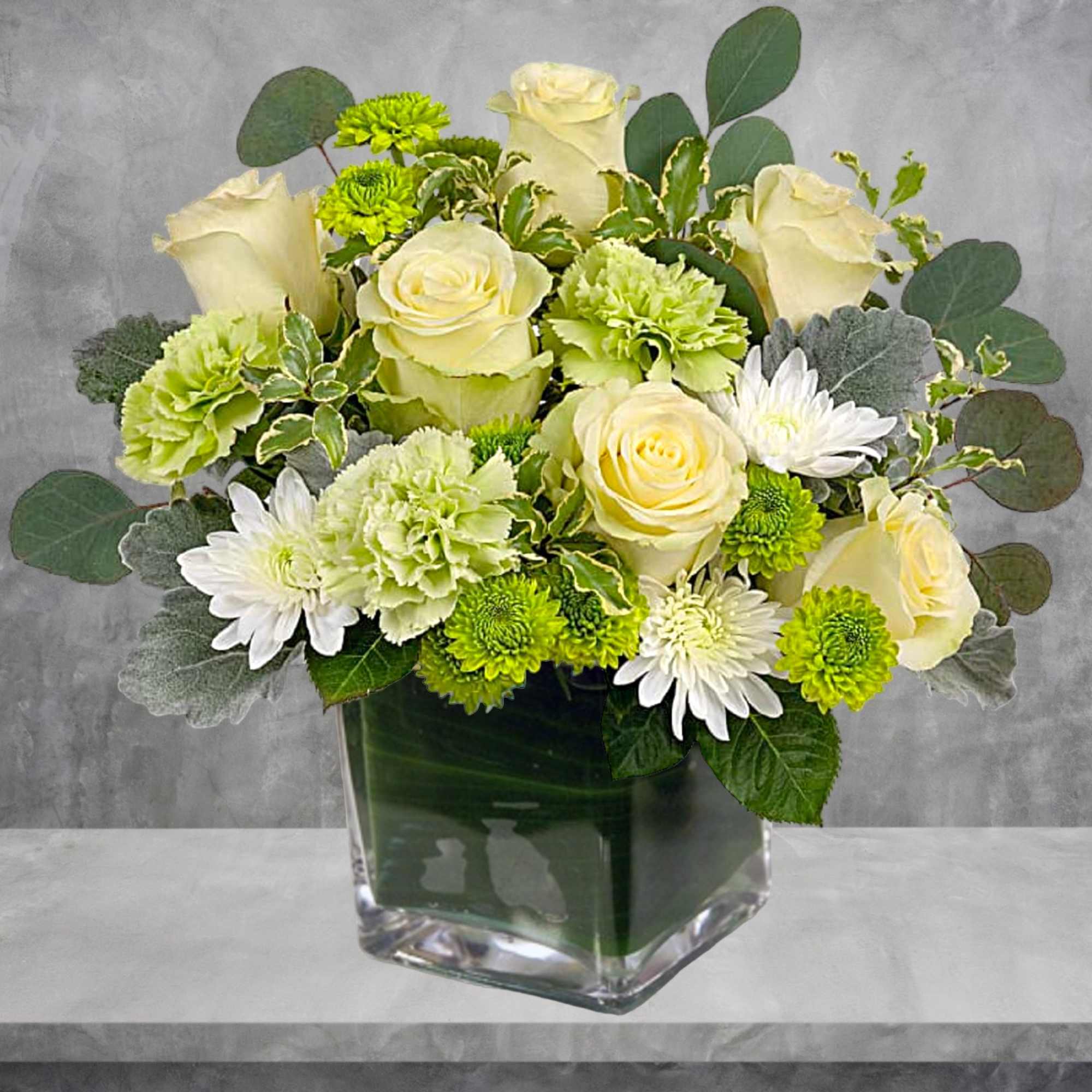 Bouquet of cream roses, green carnations, and white daisies in a glass vase
