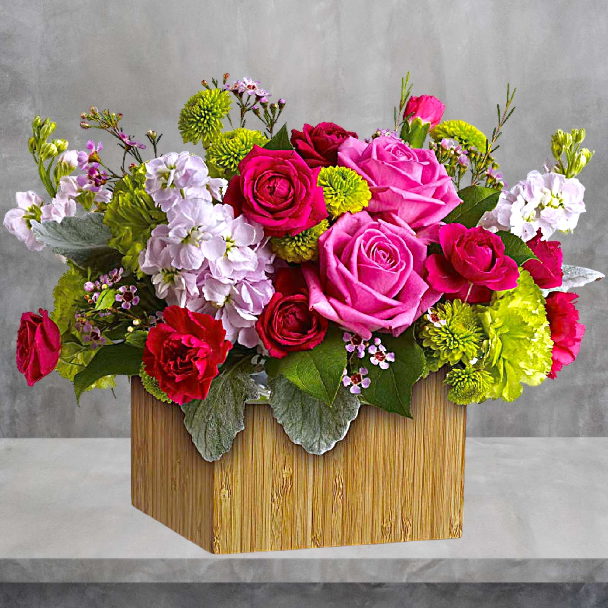 Bright pink and red rose arrangement in a wooden box with white blooms