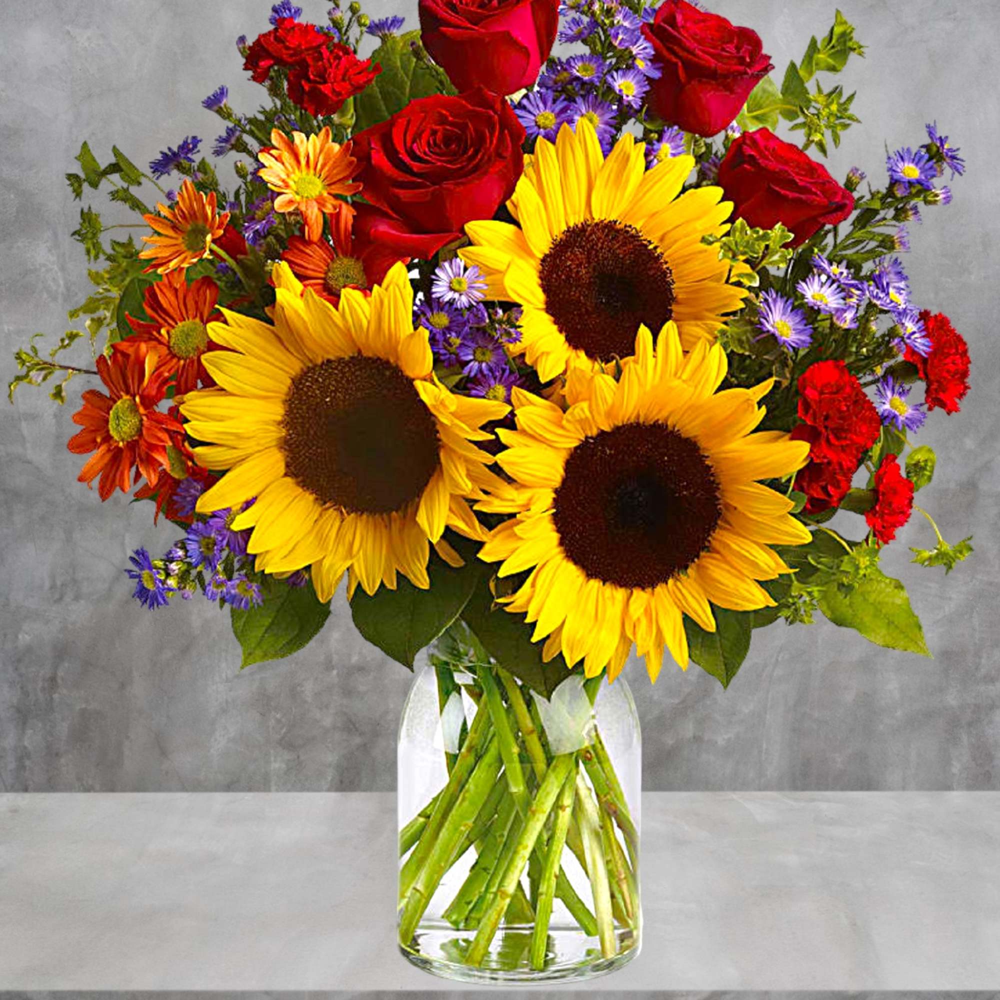 Bouquet of sunflowers, red roses, and purple daisies in a glass vase, photo 3 of 4