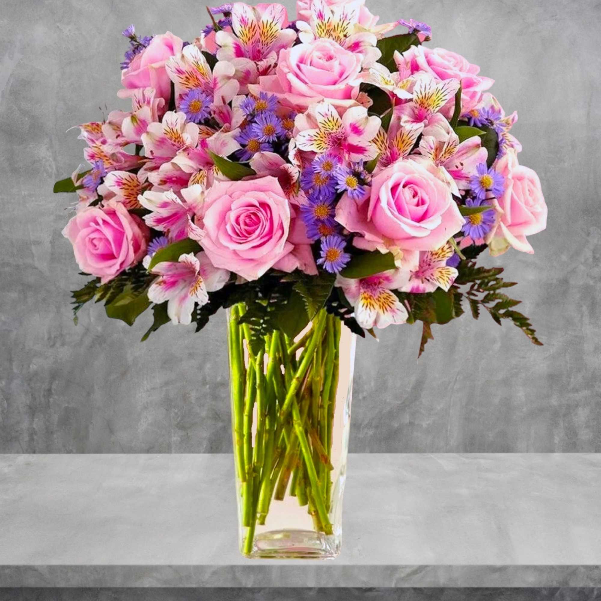 Pink roses and alstroemeria in a tall clear vase