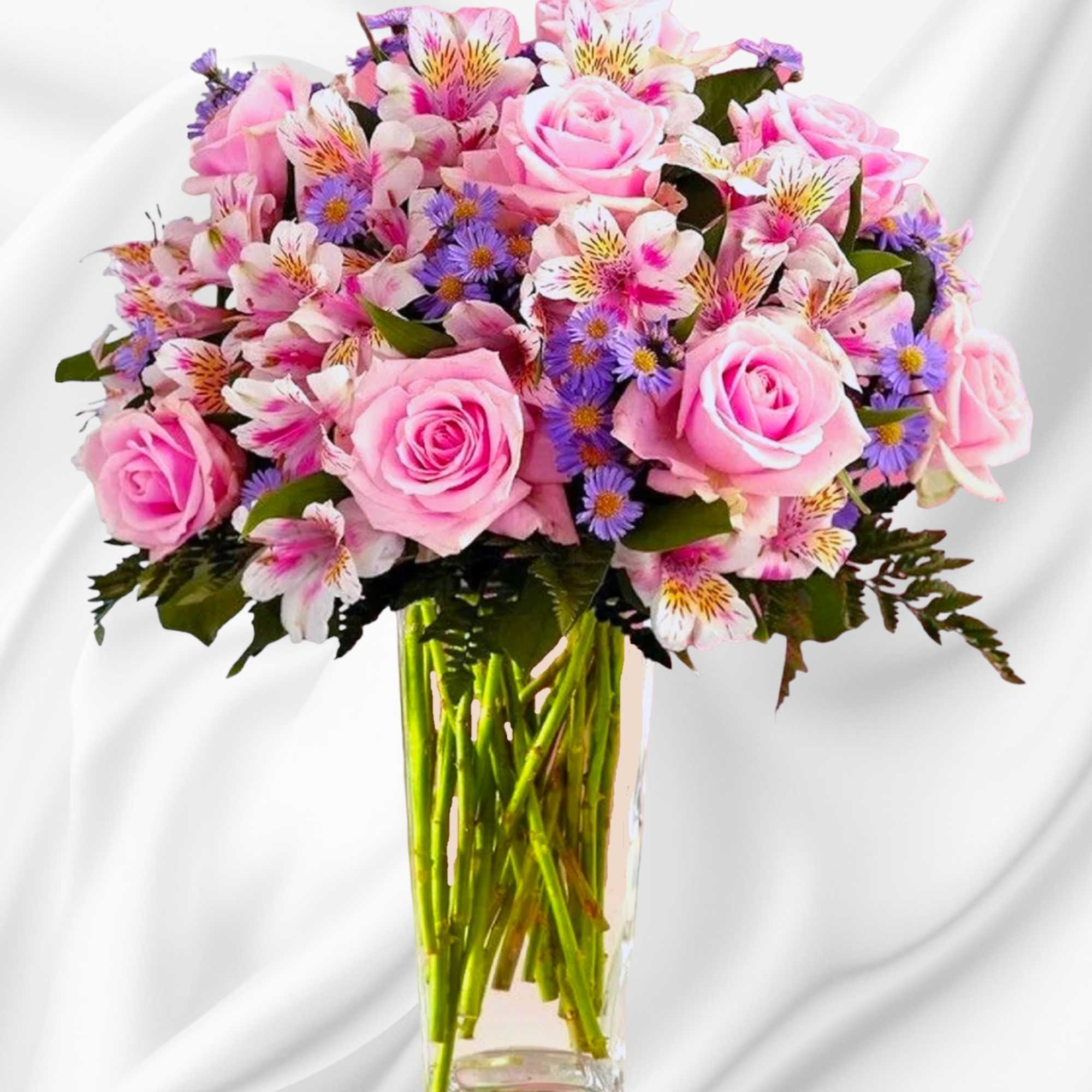 Pink roses and mixed blooms arranged in a clear glass vase