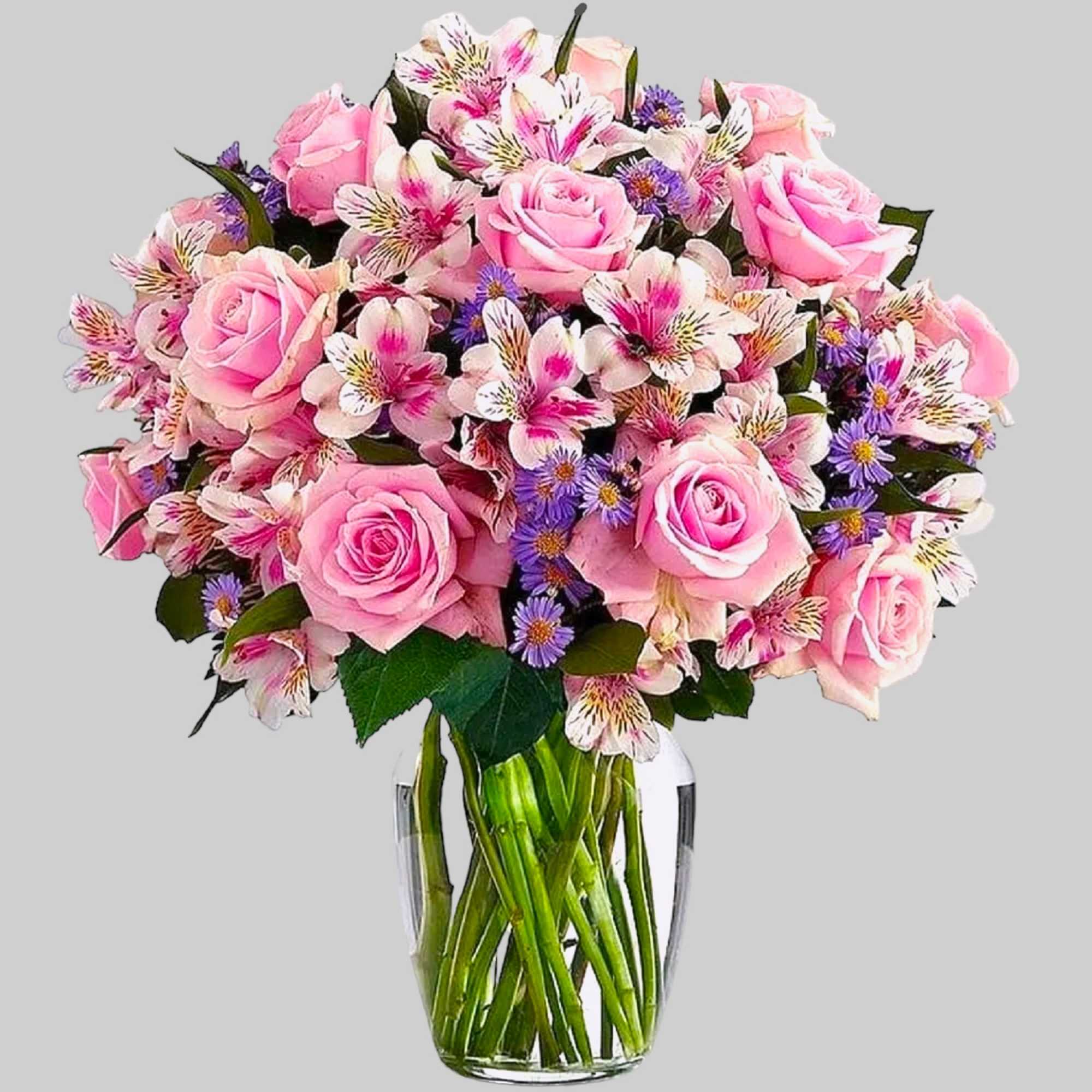 Pink roses and mixed blooms in a clear glass vase