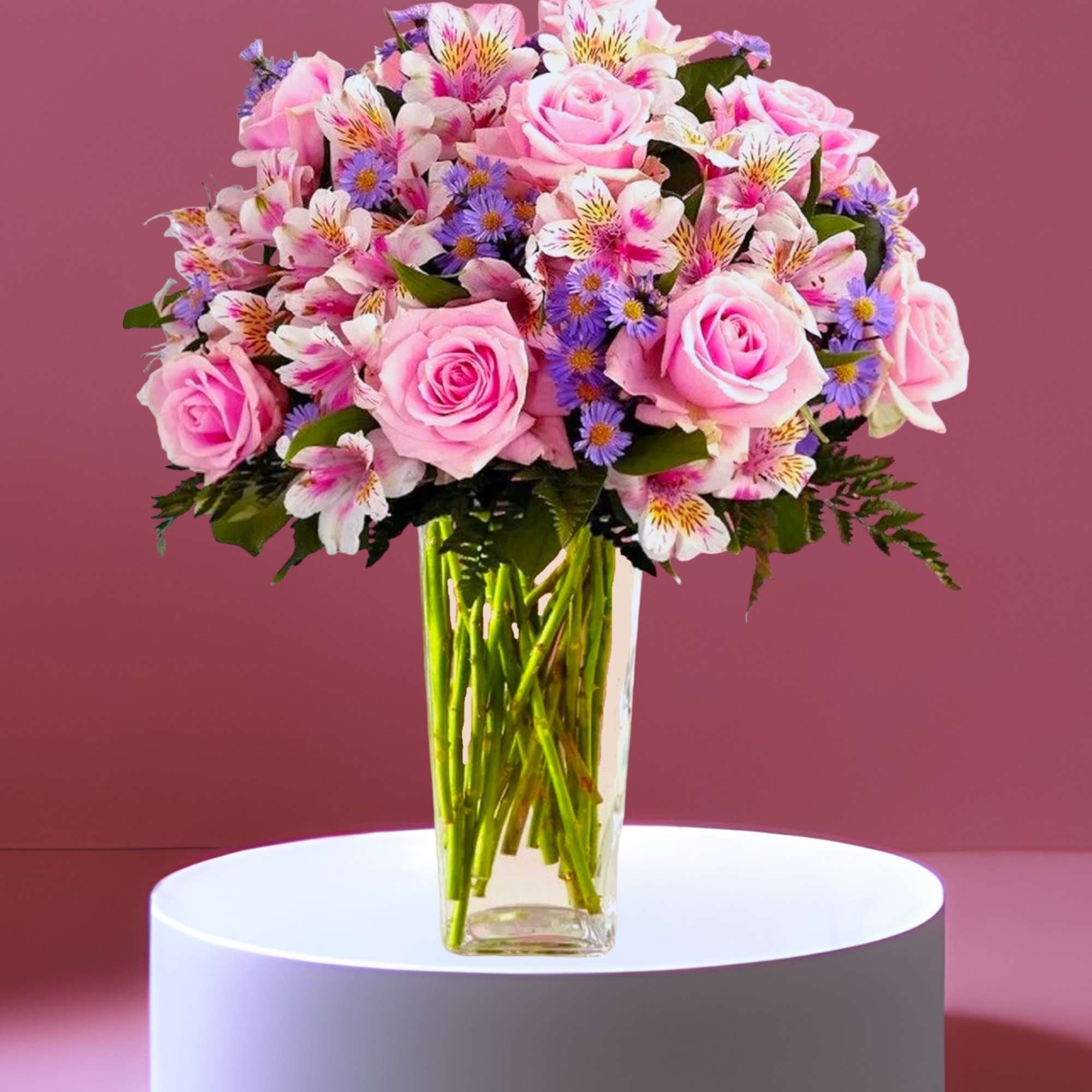 Pink roses and mixed flowers arranged in a clear glass vase