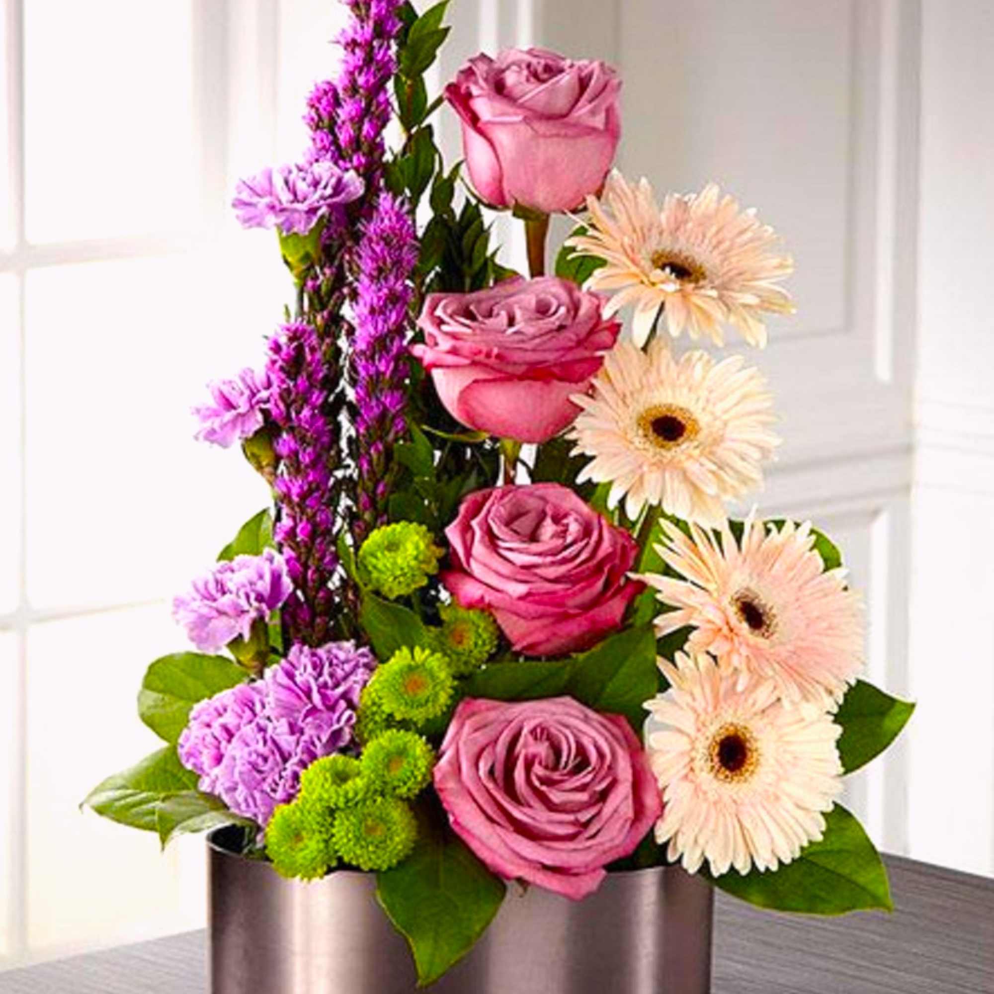 Pink roses and pale gerbera daisies in a round metal box