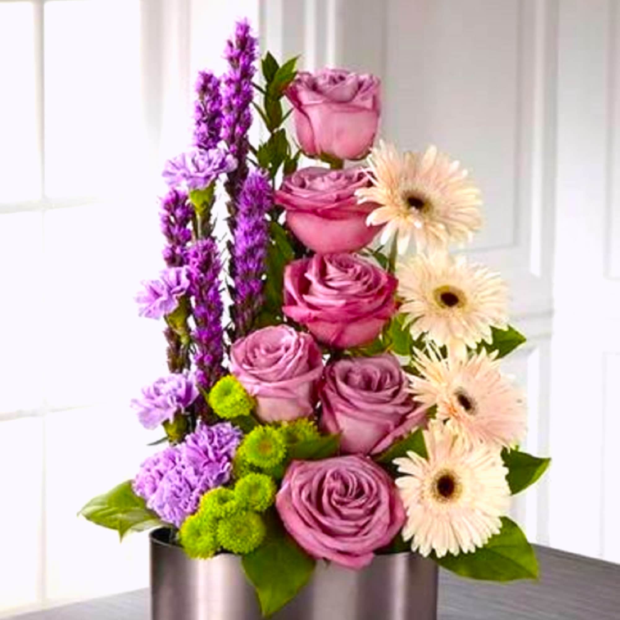 Pink and lavender roses with purple spikes and pale gerbera daisies in a silver box