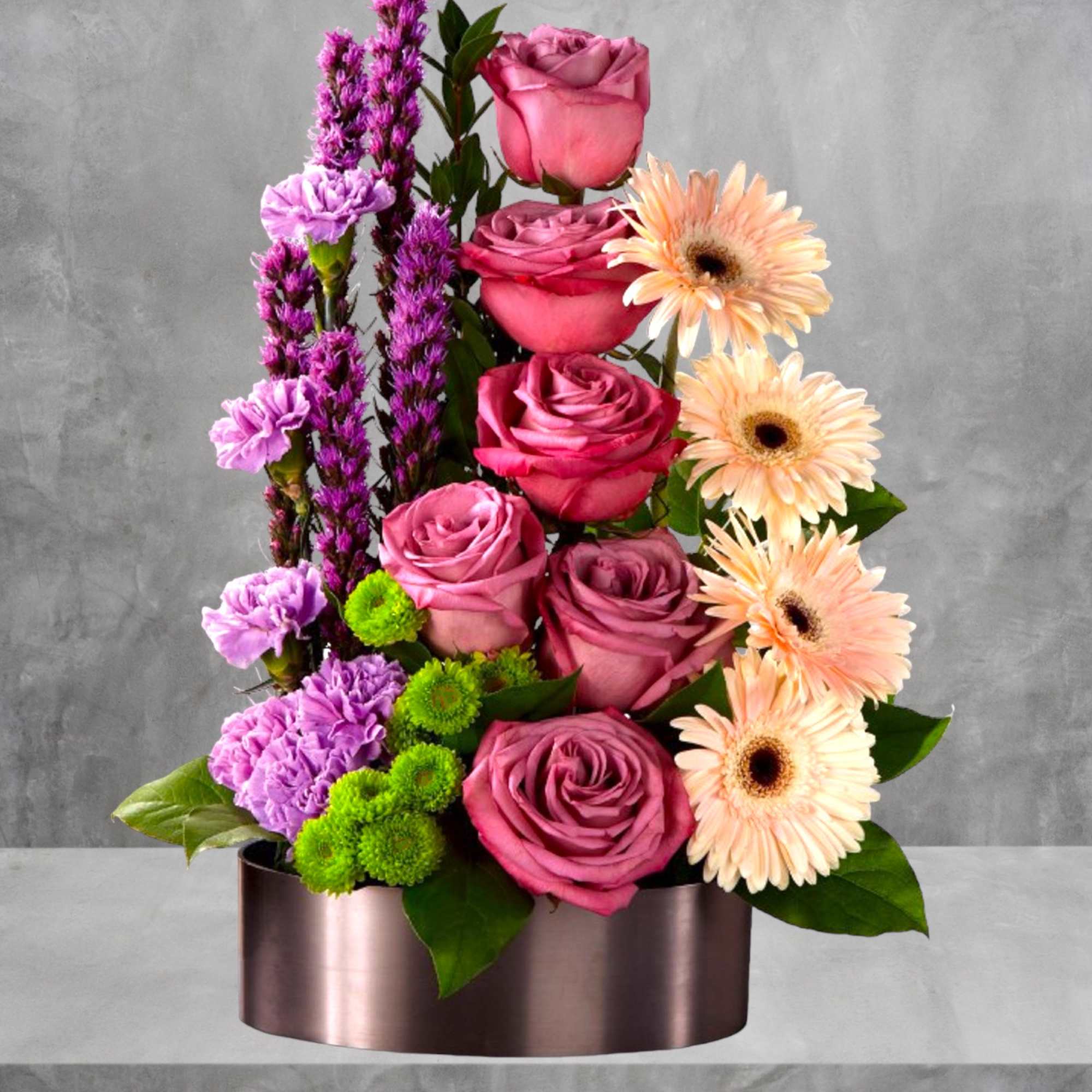 Pink roses and peach gerbera daisies in a round metallic box