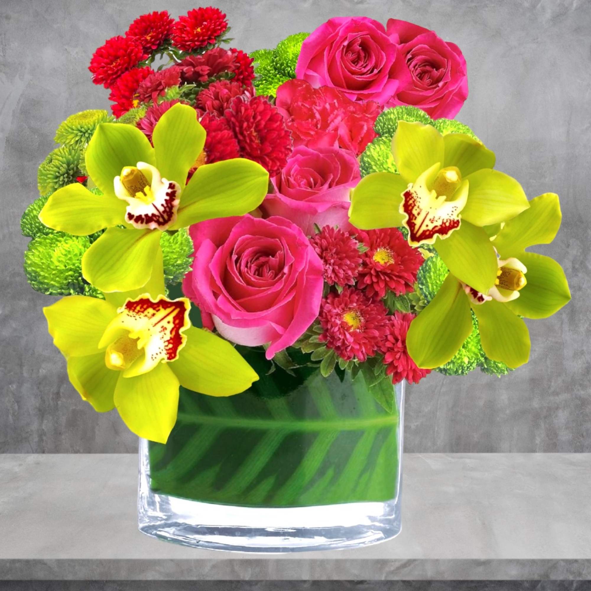 Pink roses and bright yellow orchids in a clear glass vase