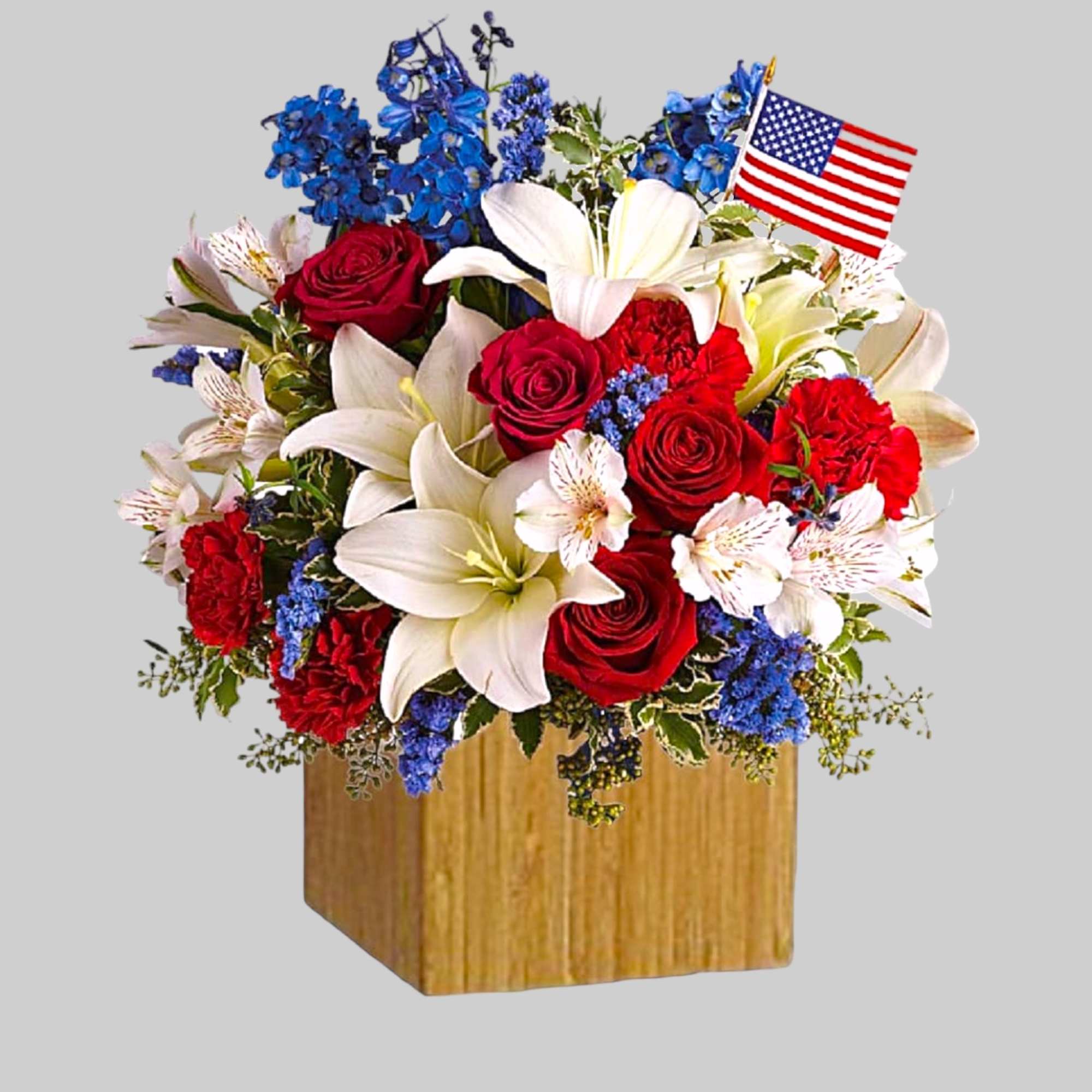 Red roses and white lilies in a wooden box with a small American flag