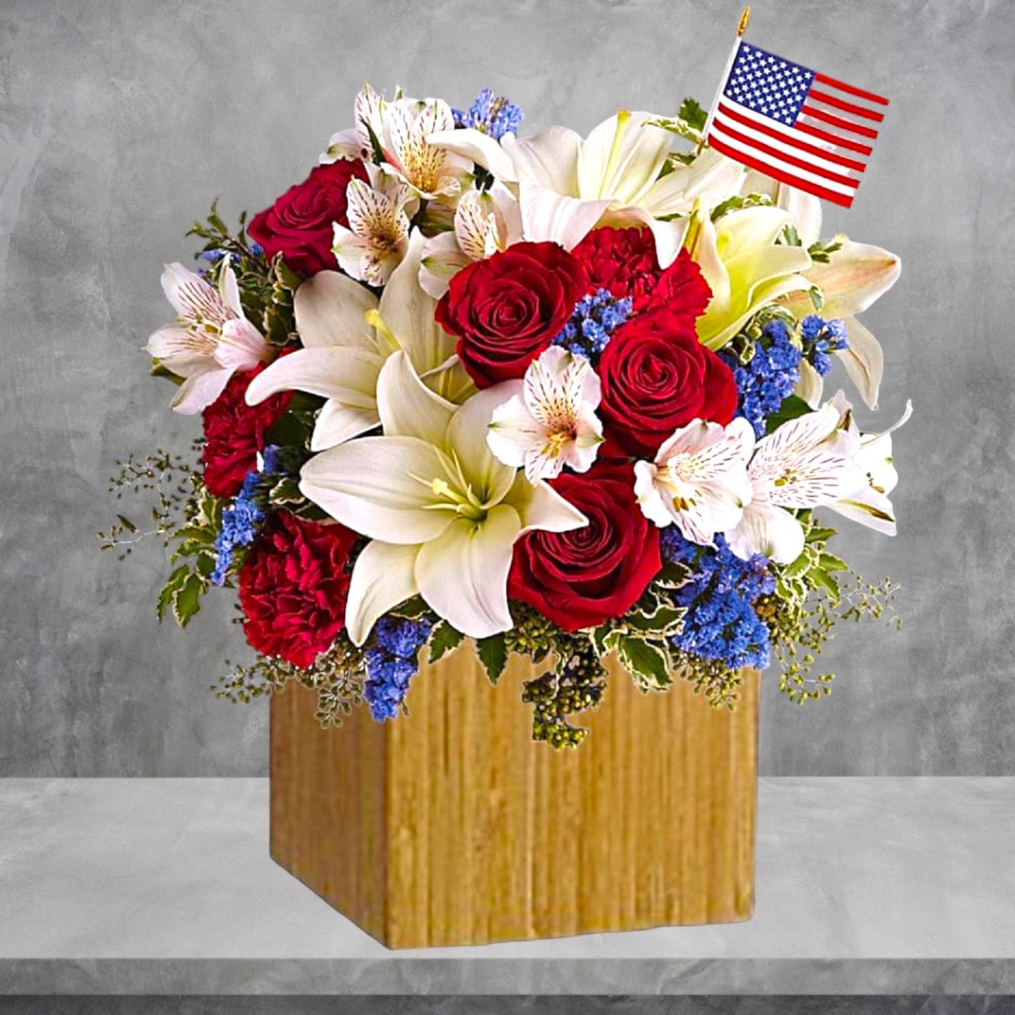 Bouquet of red roses and white lilies in a wooden box with a small American flag