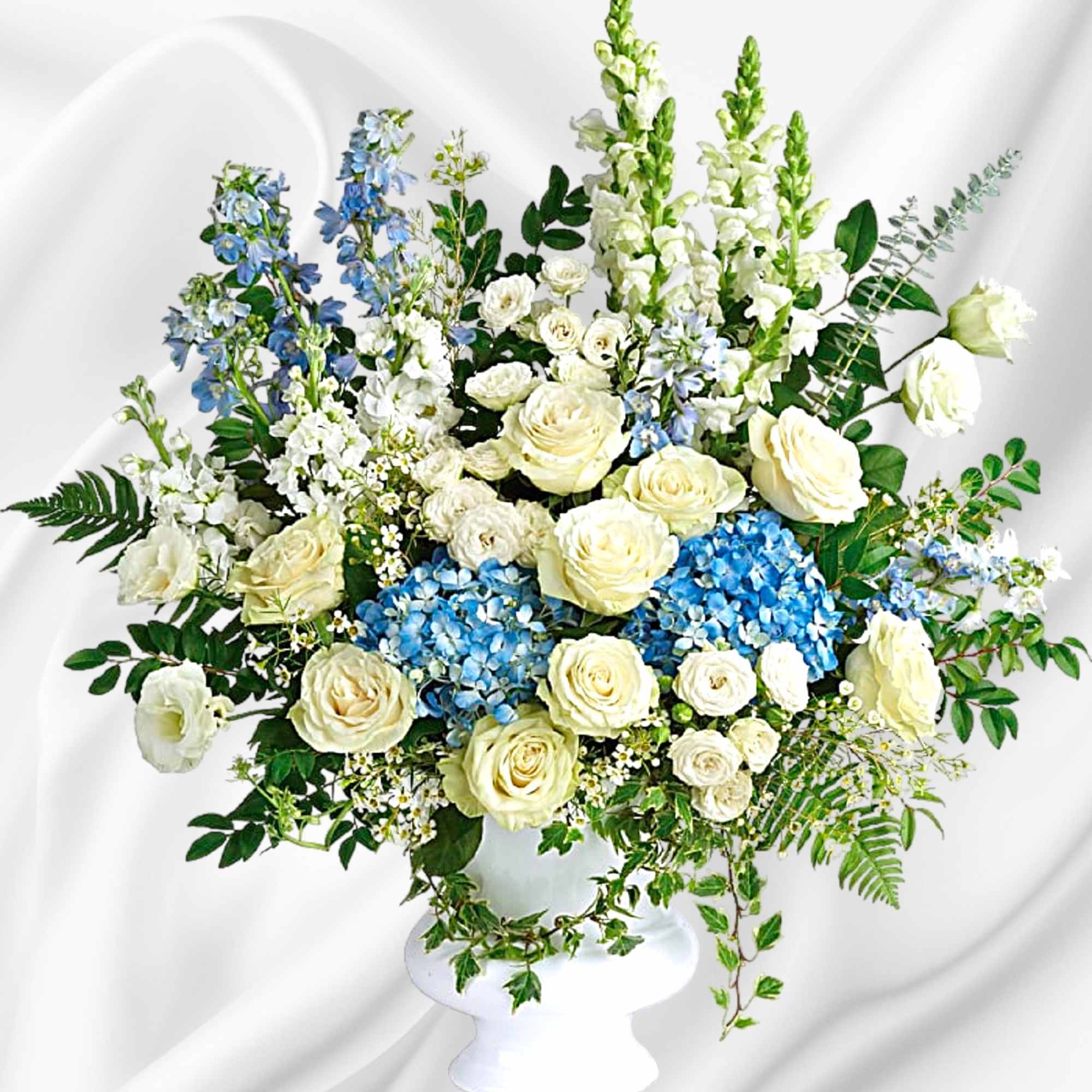 White roses and blue flowers arranged in a white pedestal vase, photo 2 of 4