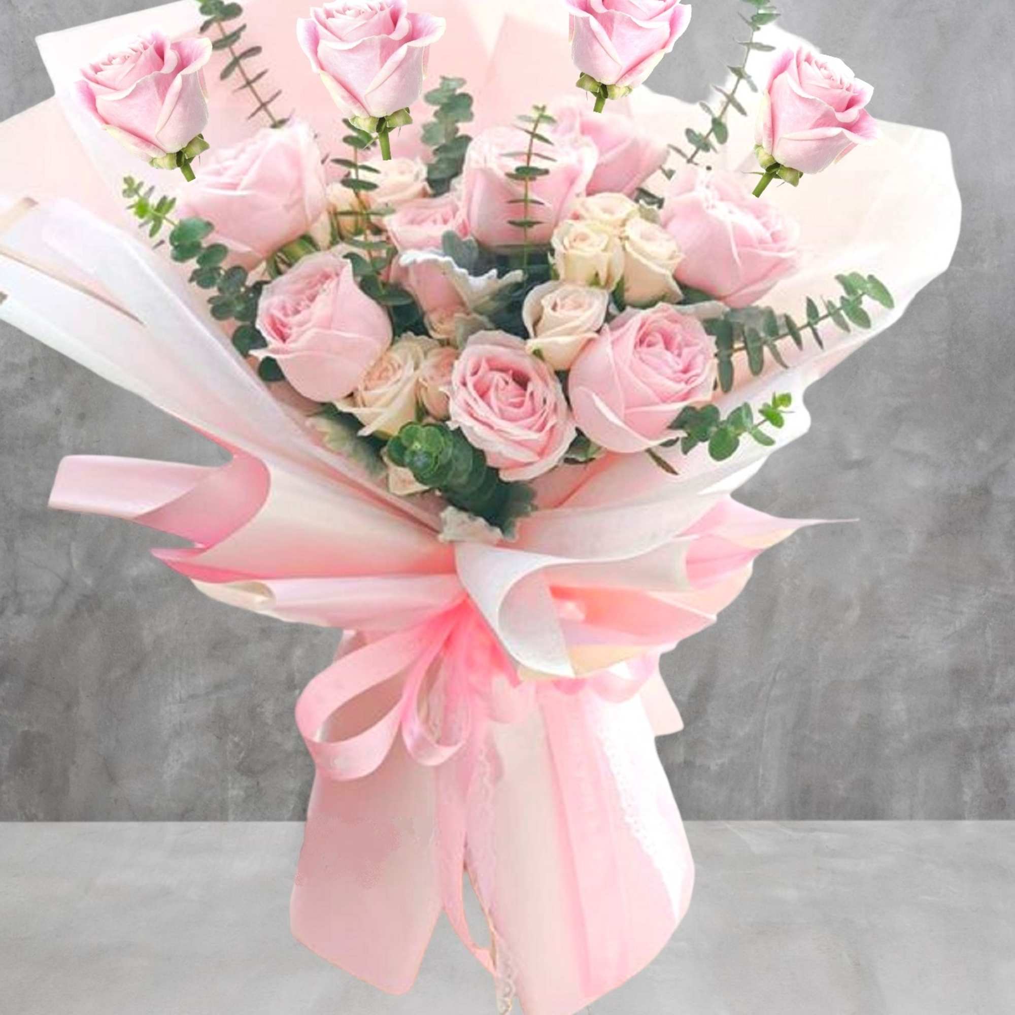 Bouquet of pink roses wrapped in pale pink paper with ribbon