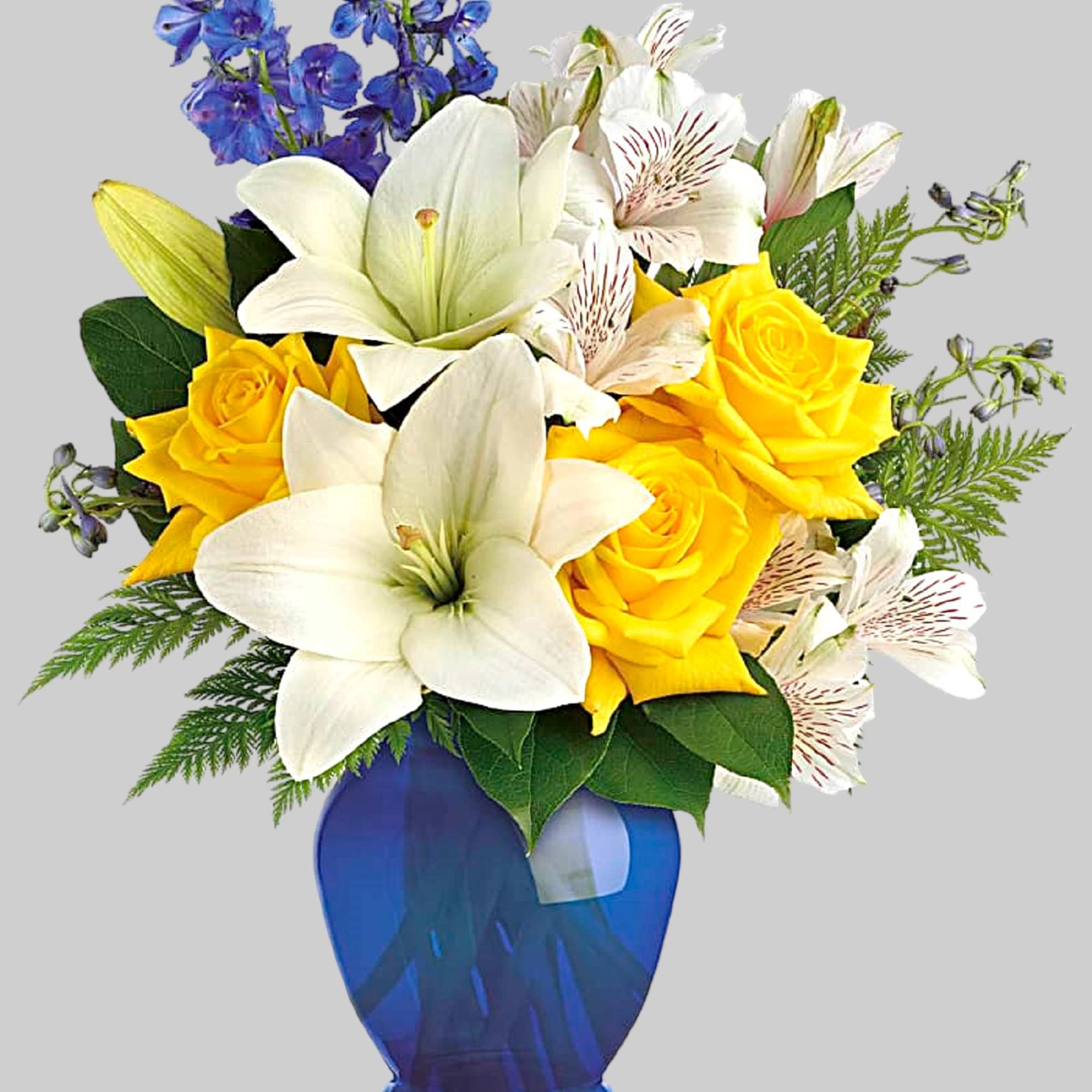 Bouquet of yellow roses, white lilies, and blue flowers in a blue vase