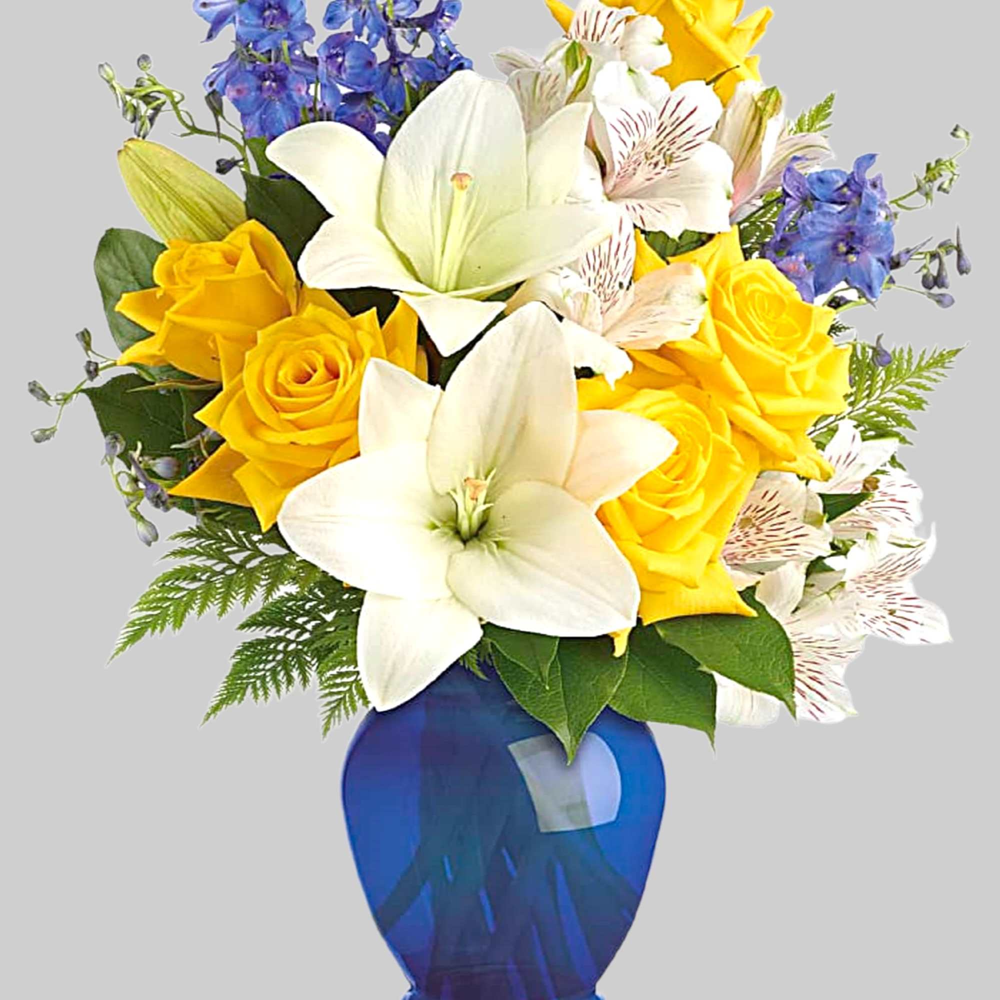 Yellow roses and white lilies in a blue glass vase
