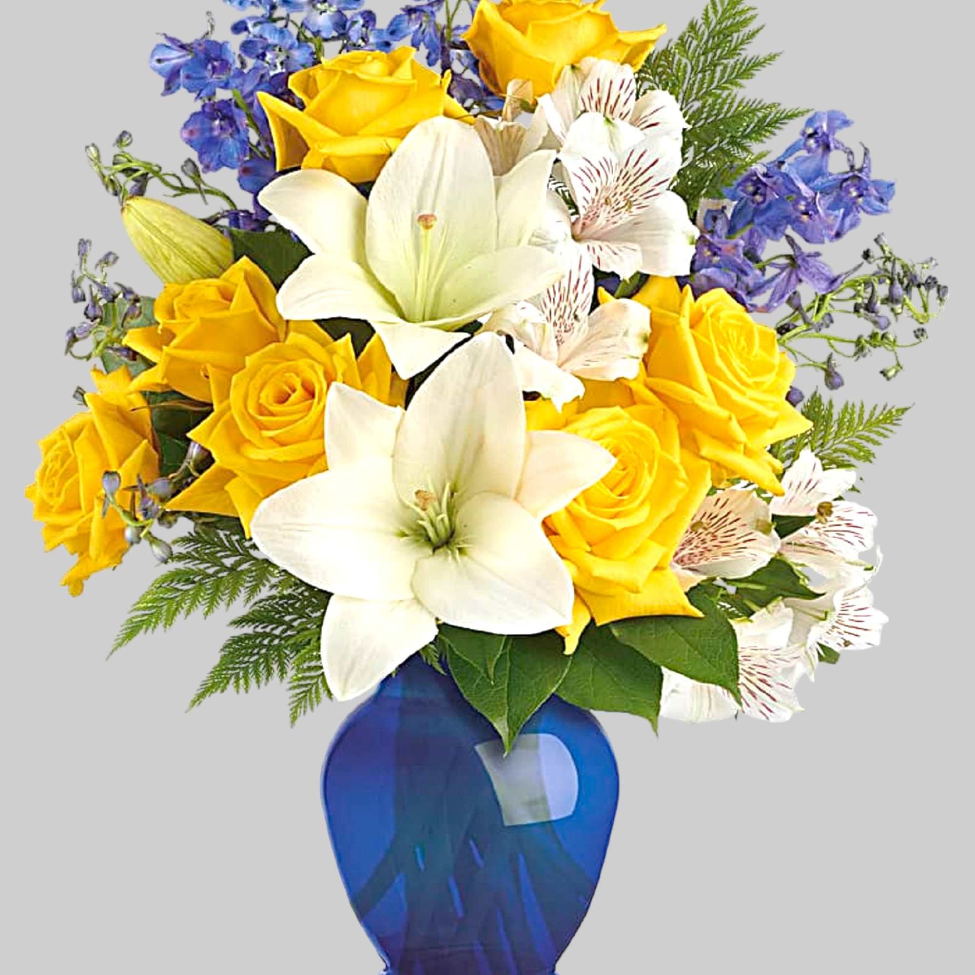Yellow roses and white lilies in a blue glass vase