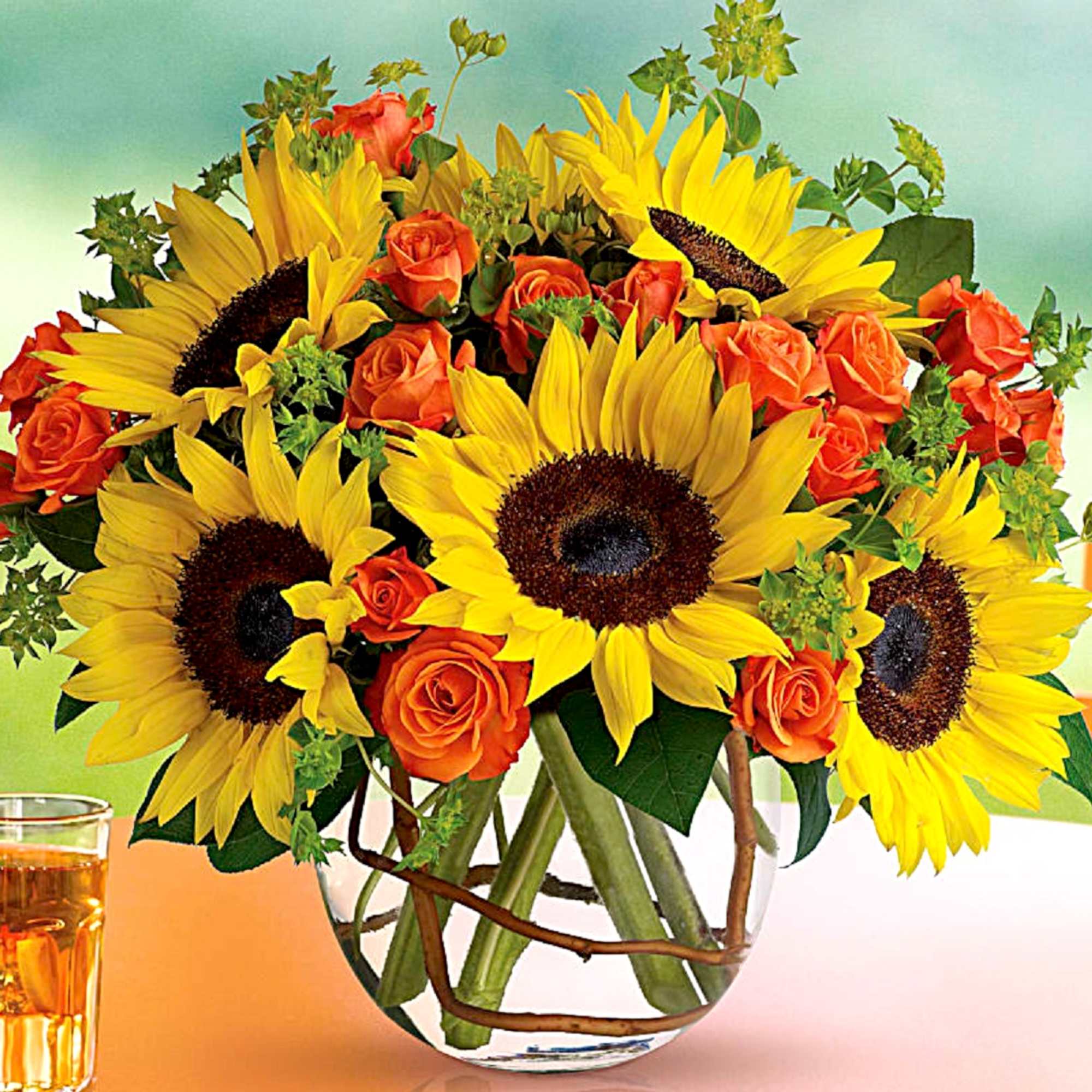 Bouquet of yellow sunflowers and orange roses in a clear glass vase