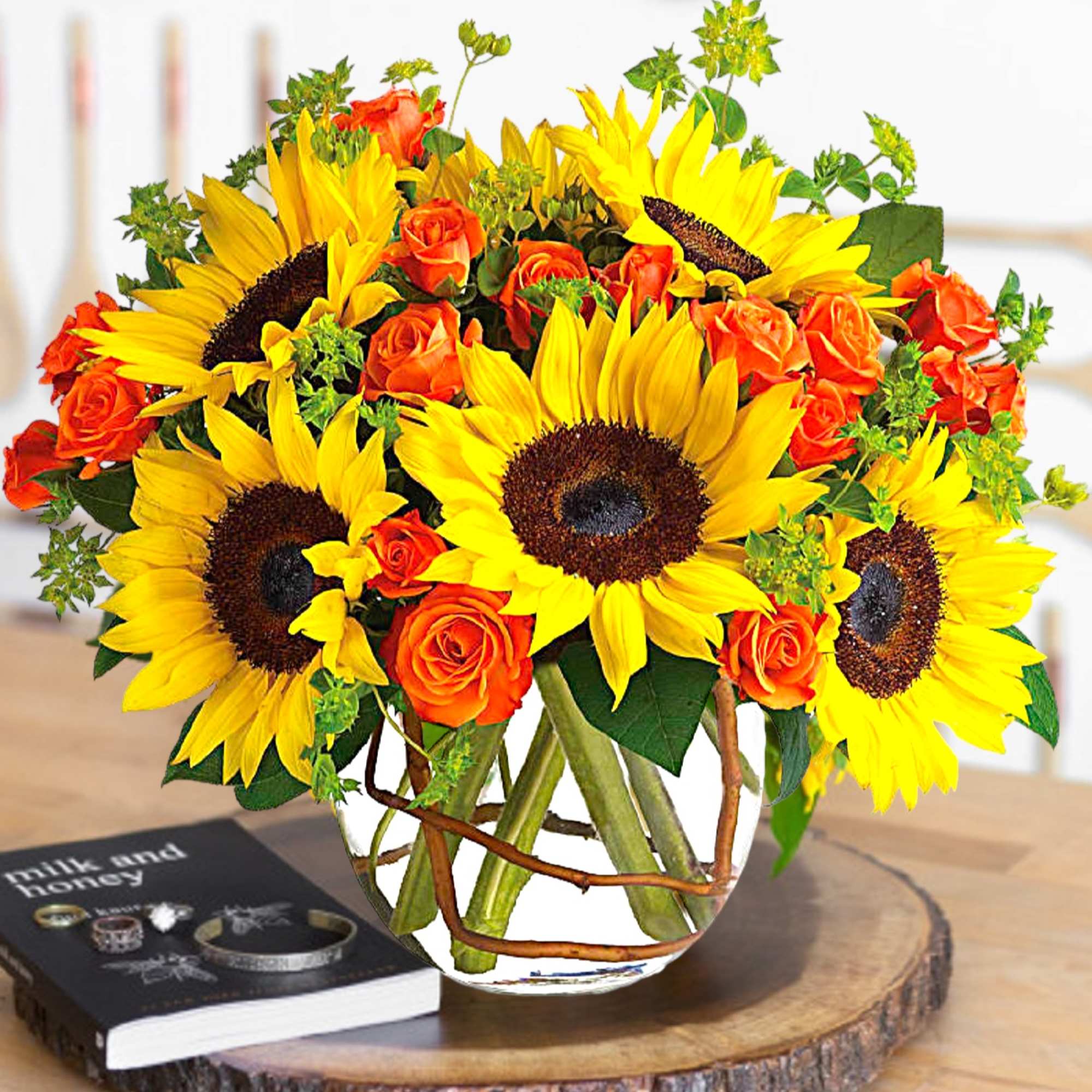 Sunflowers and orange roses arranged in a glass vase.