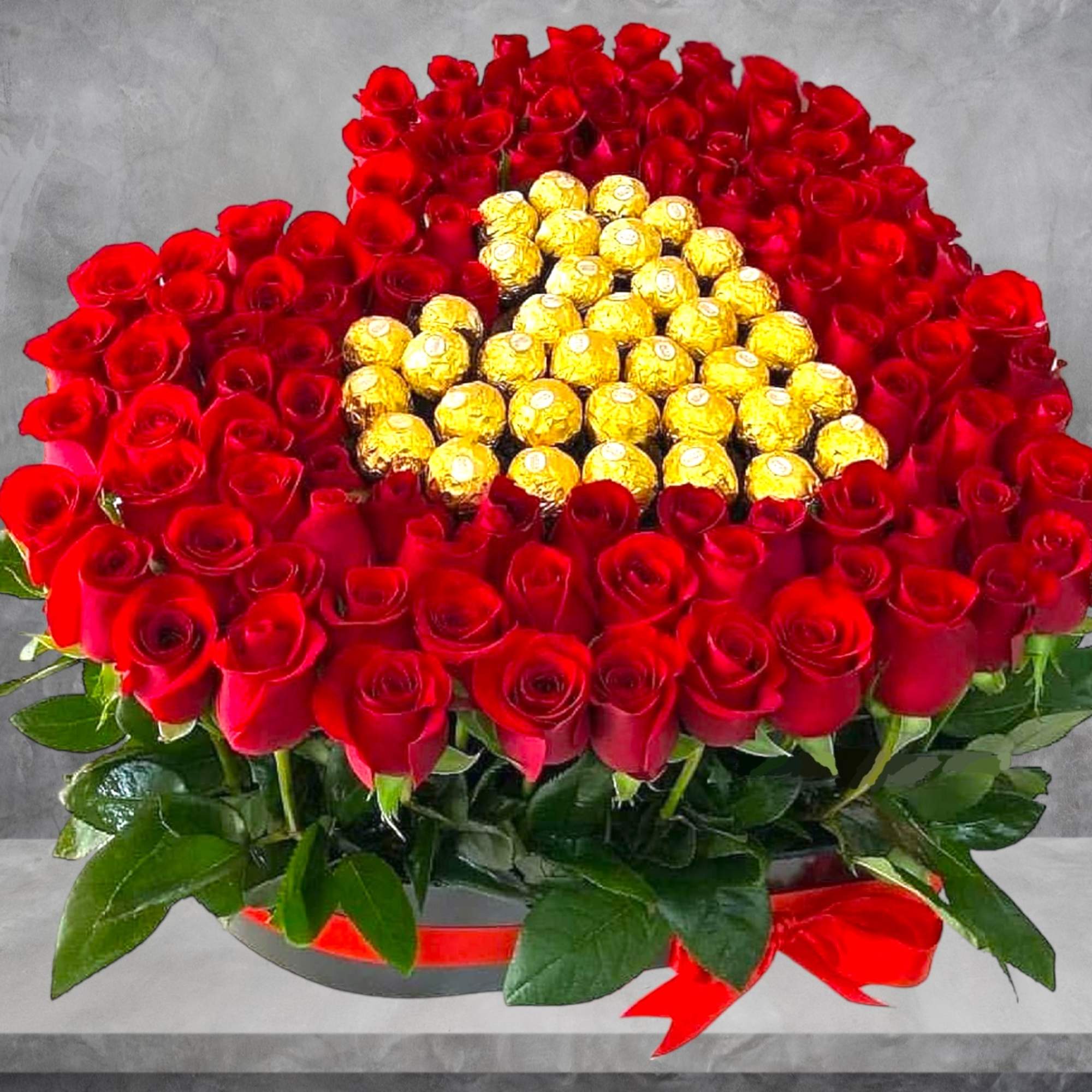 Red roses arranged around gold-wrapped chocolates in a round box