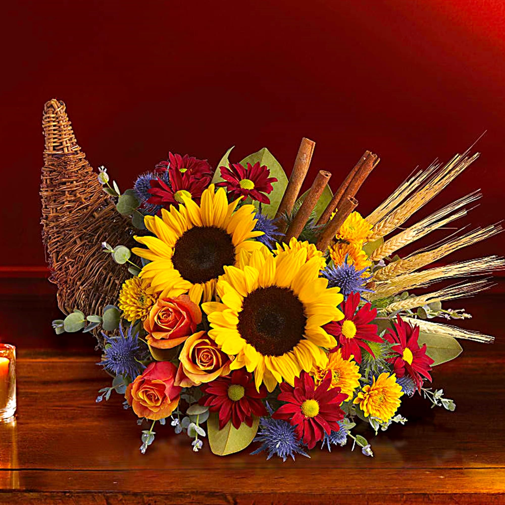 Sunflower and rose arrangement with wheat and cinnamon sticks in a wicker cornucopia