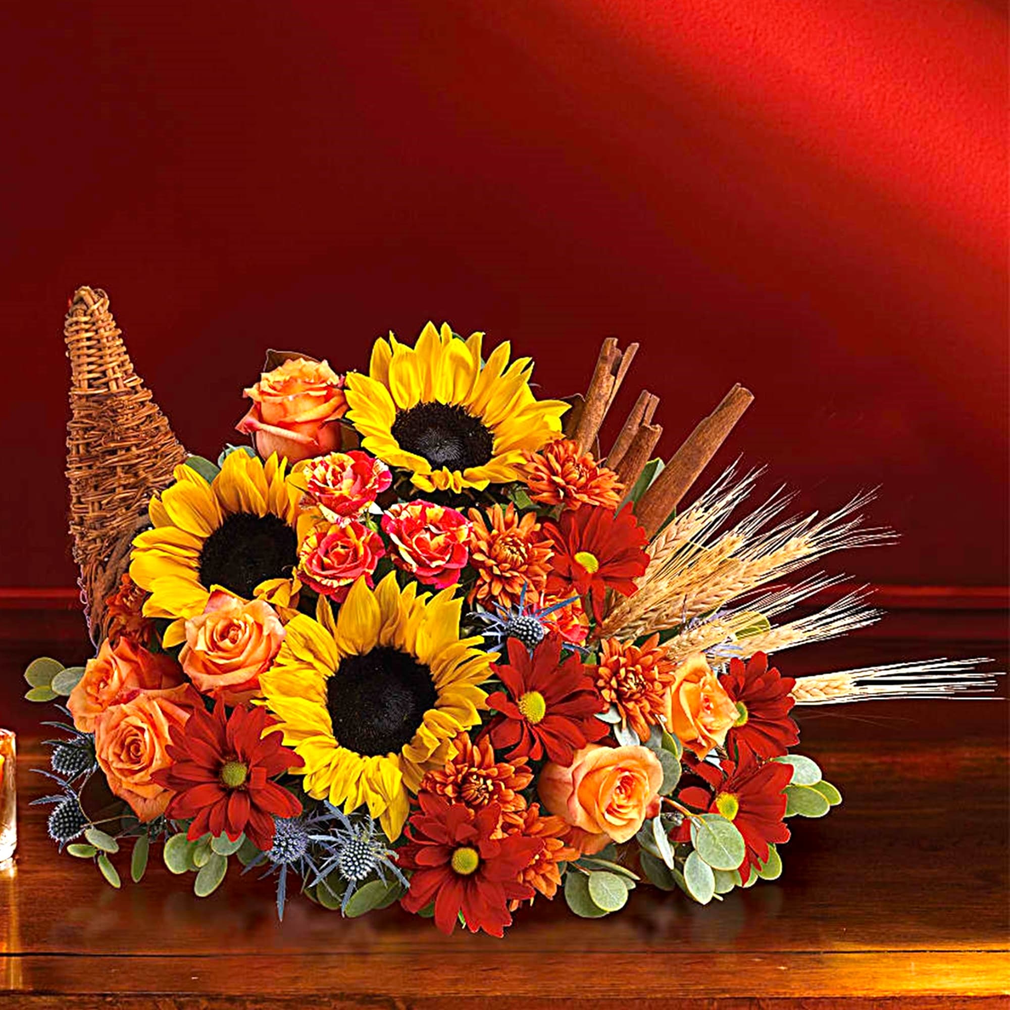 Sunflowers and orange roses arranged in a wicker basket with wheat accents