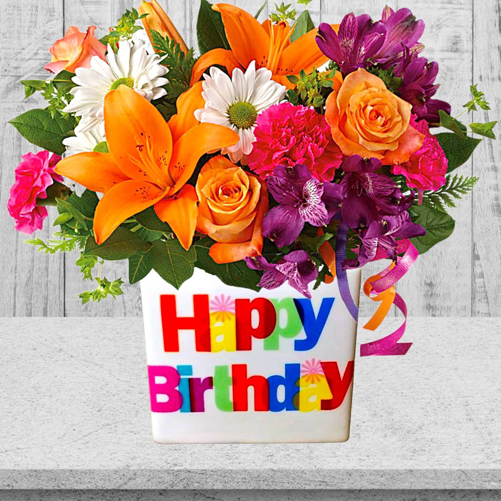 Colorful mixed flower arrangement in a white Happy Birthday vase