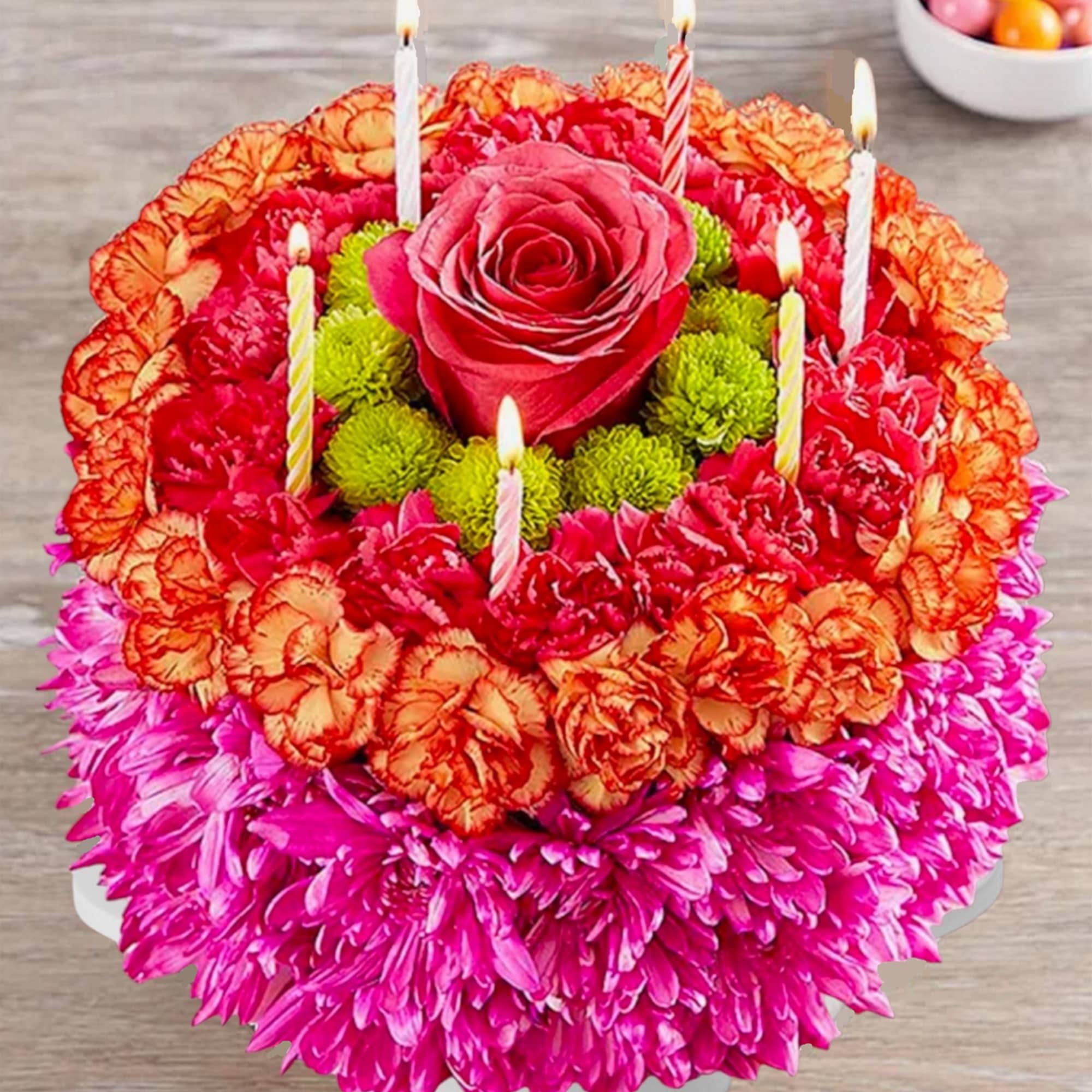 Round floral cake with a rose center and lit birthday candles